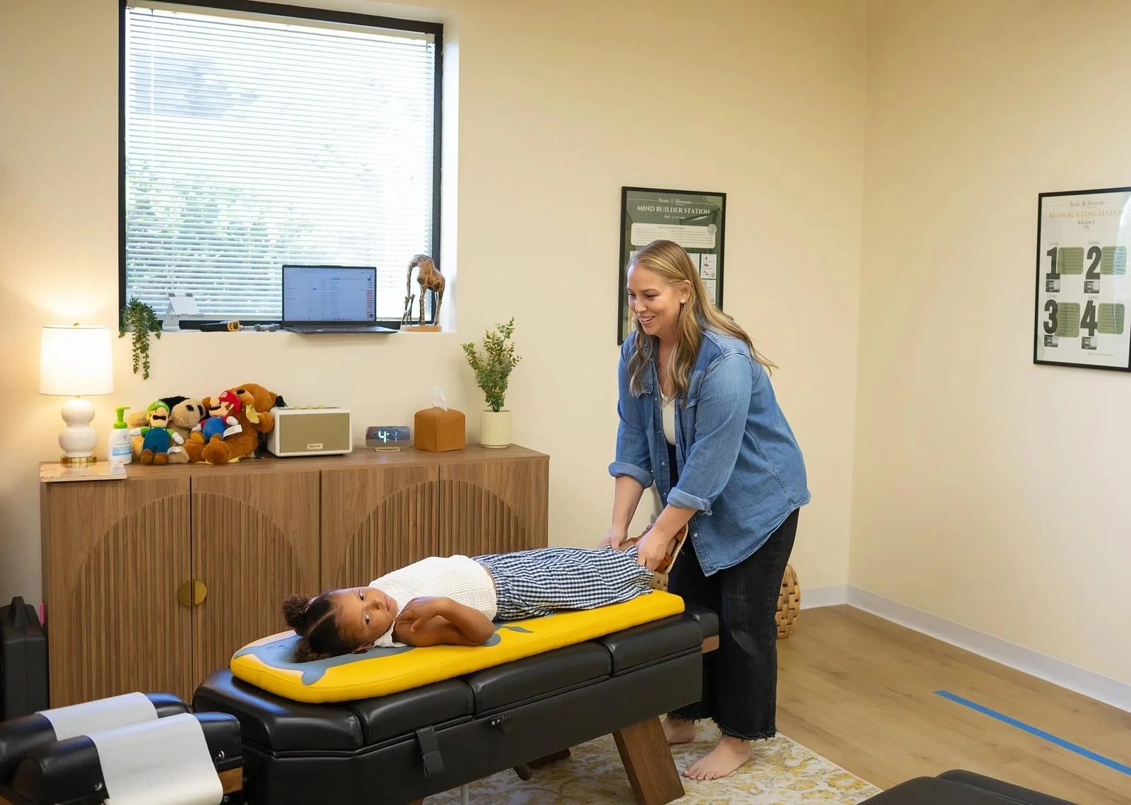 Dr. Jennifer Gordon checking a child’s leg alignment while the child lies on a pediatric chiropractic table.