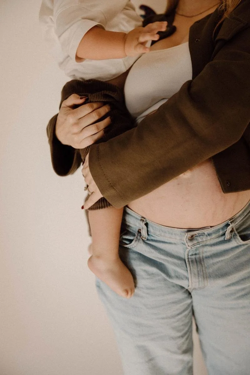 Pregnant mother holding her toddler with her baby bump visible.