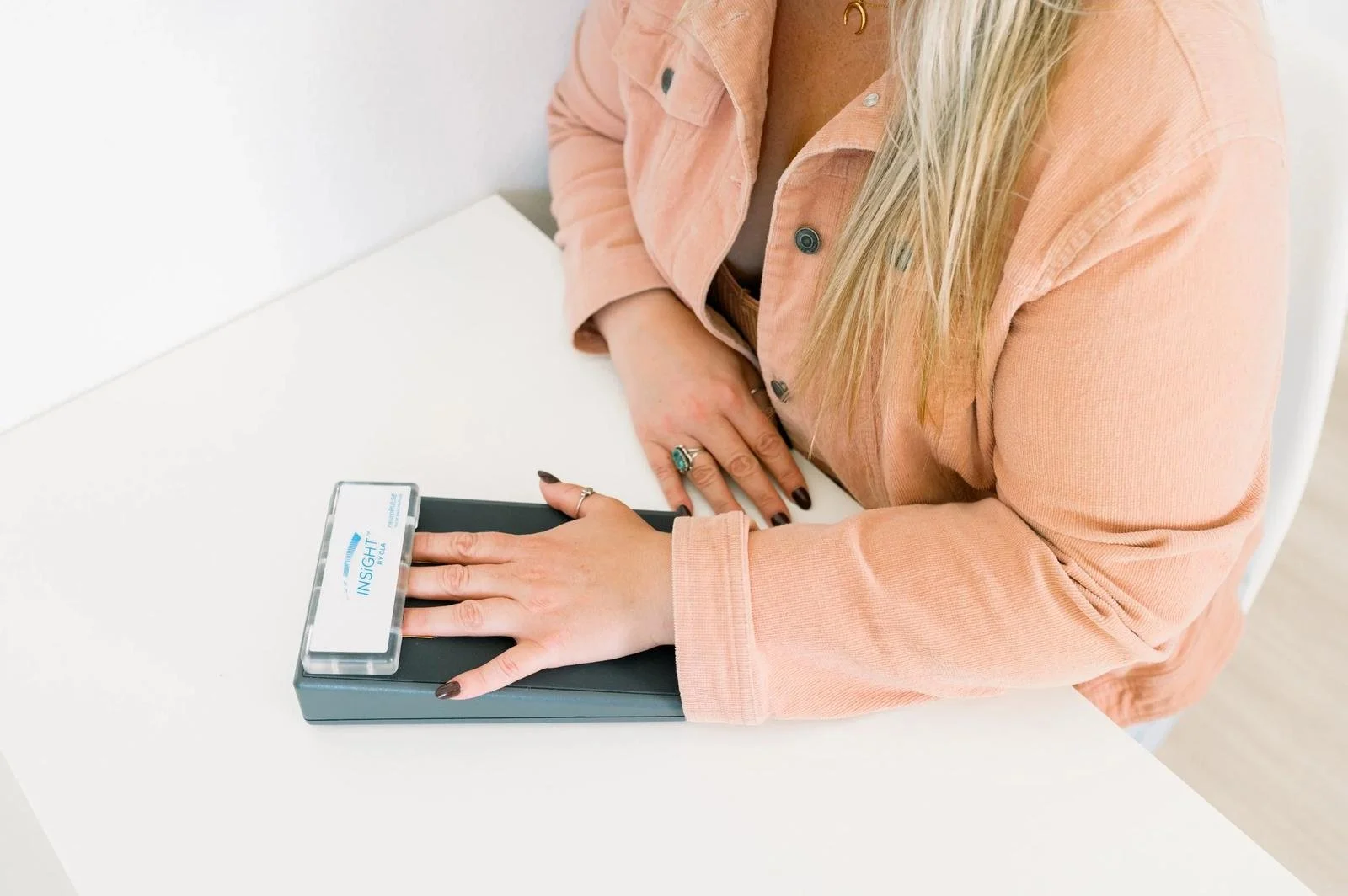 Patient placing a hand on an INSiGHT scanning device during a chiropractic assessment at Taproot Chiropractic.