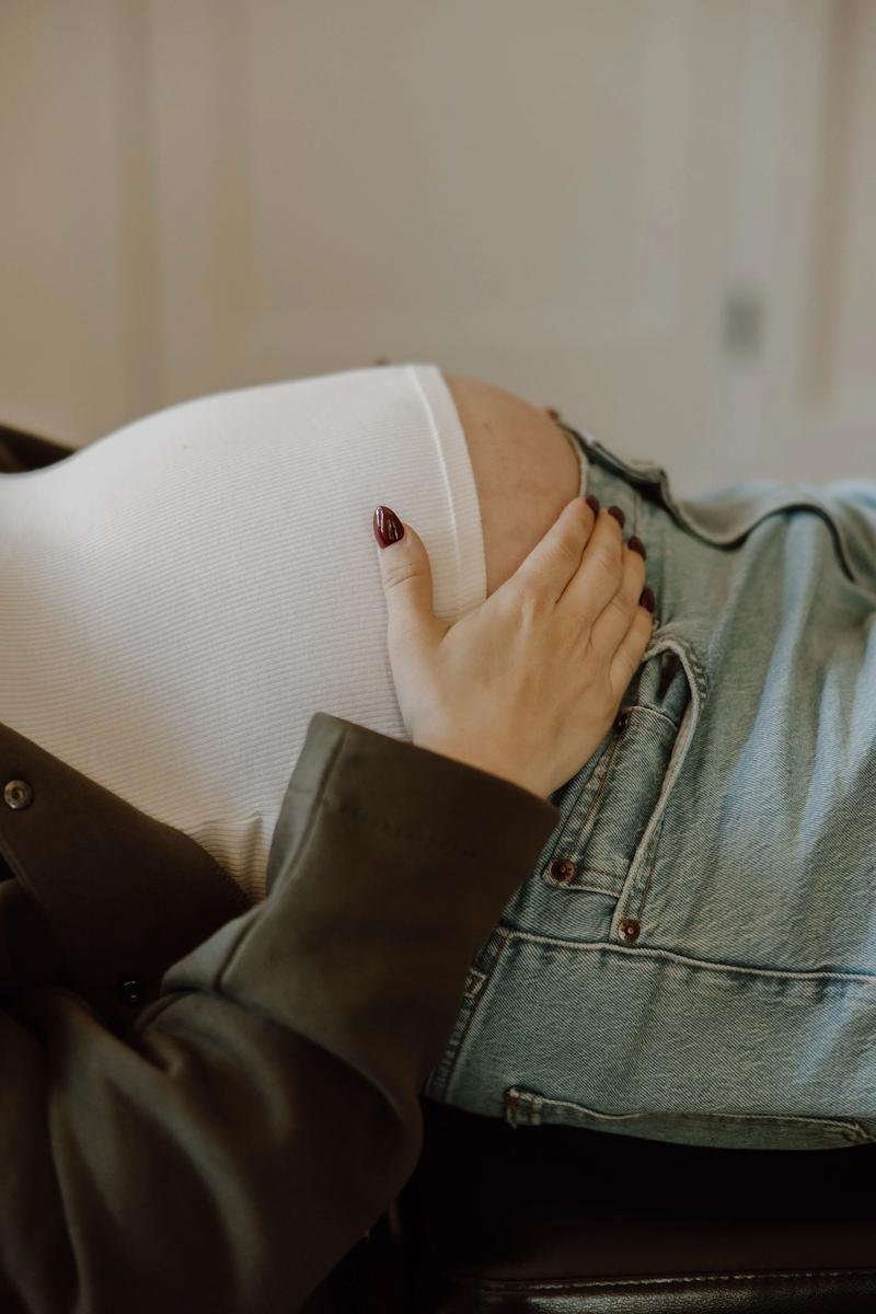 Close-up of a pregnant patient reclining with one hand resting on her baby bump.