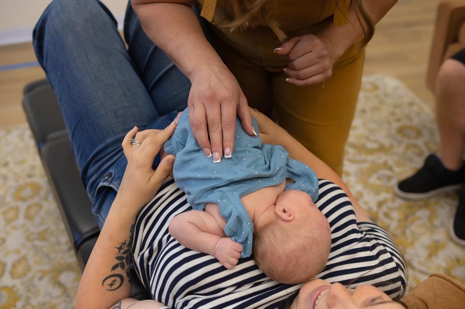 Chiropractor gently adjusting an infant resting on a parent’s chest at Taproot Chiropractic.