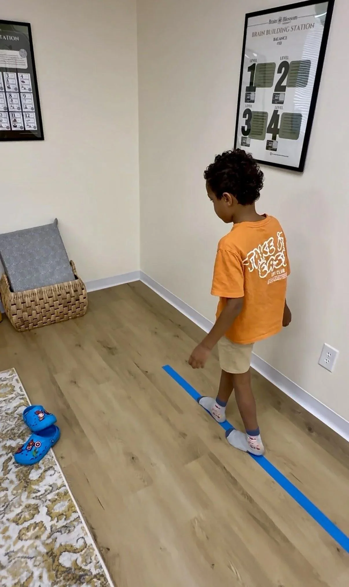 Young boy walking along a balance line on the floor during a movement and coordination activity.