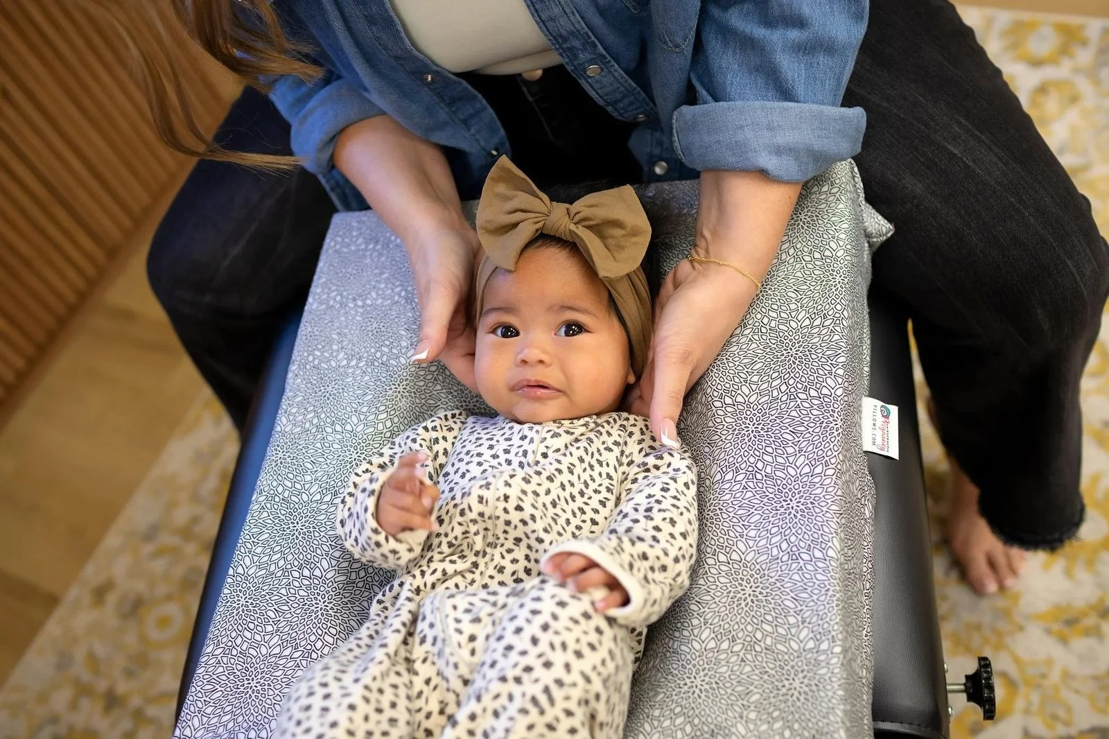 Dr. Jennifer Gordon gently supporting an infant’s head and neck during an assessment at Taproot Chiropractic.