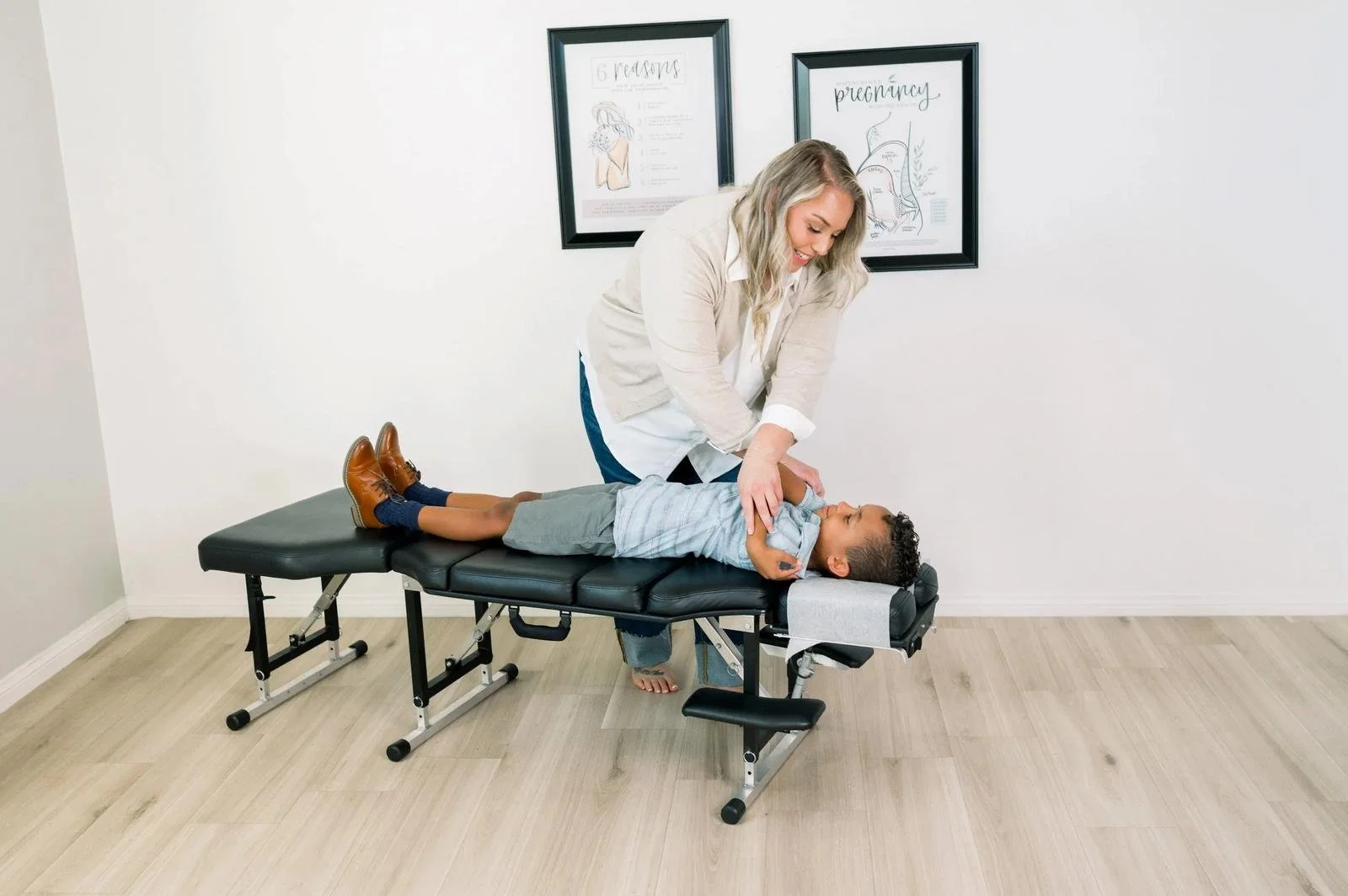 Dr. Jennifer Gordon providing a gentle chiropractic adjustment to a young boy lying on his back on a treatment table.