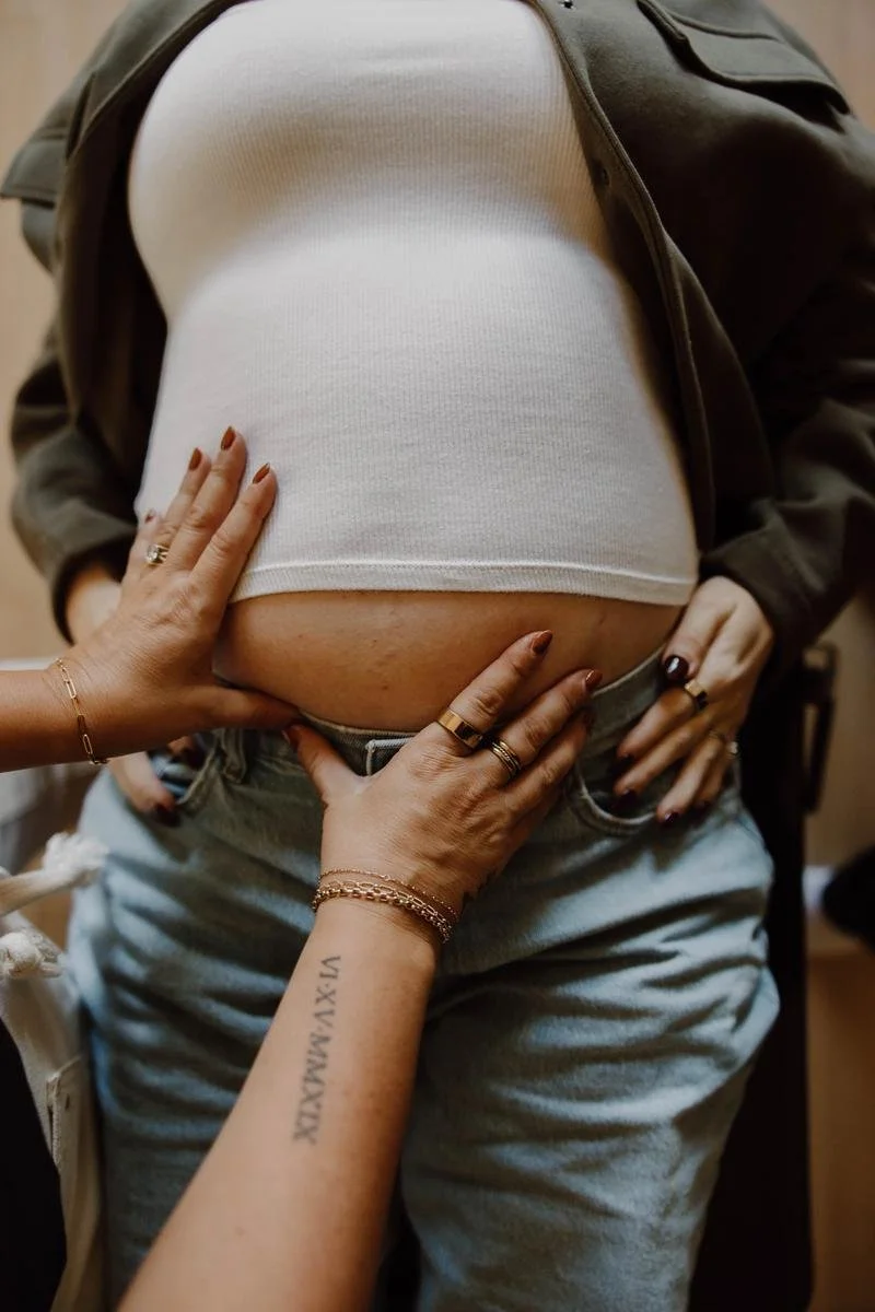 Close-up of a pregnant patient receiving a gentle abdominal and pelvic assessment.