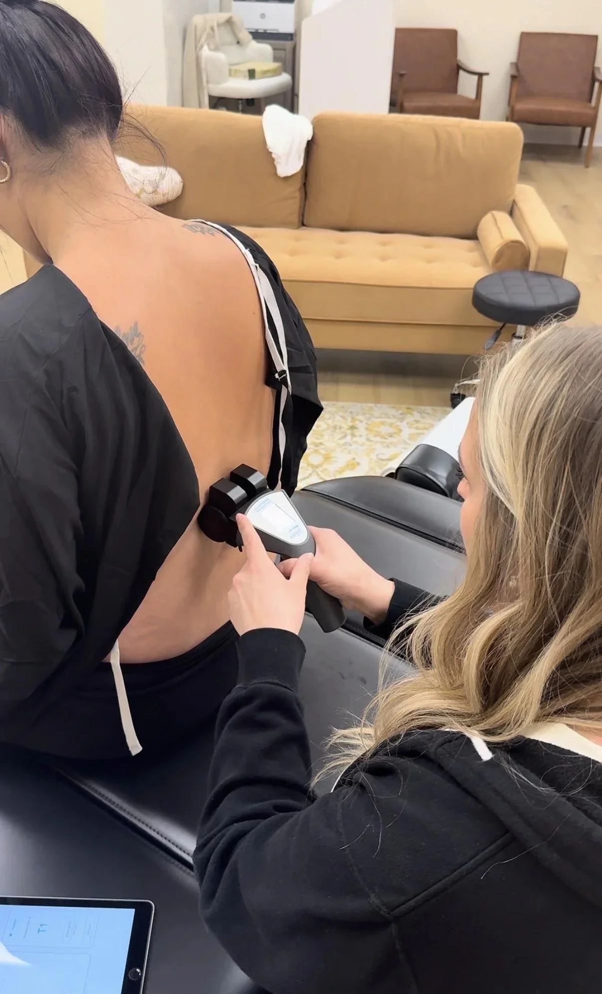 Dr. Jennifer Gordon using a handheld INSiGHT scanning device on a seated patient’s lower back.