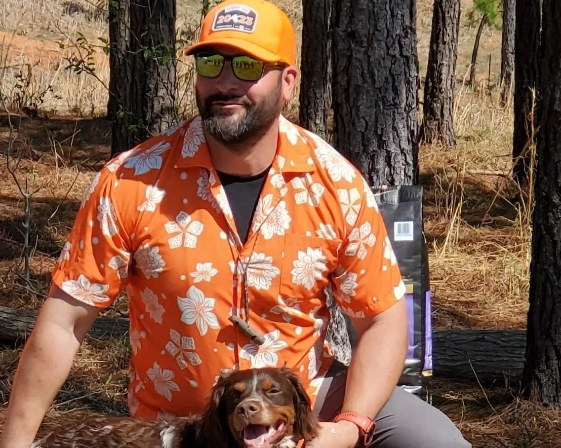 Photo of Mike Strup in an orange Hawaiian shirt showing a dog