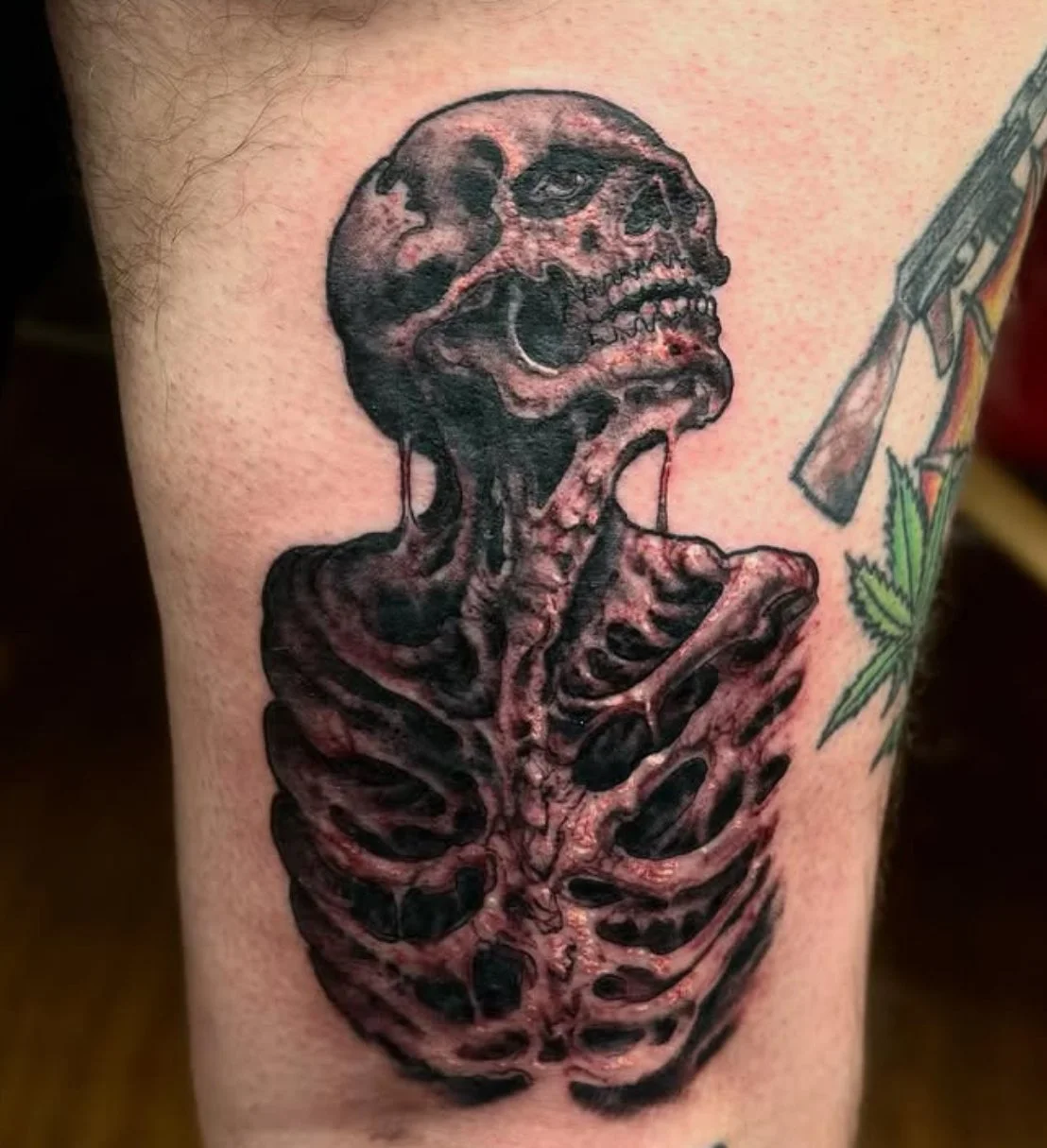 Tattoo of a skull with a skeleton torso, with the skull appearing to be melting or dripping.