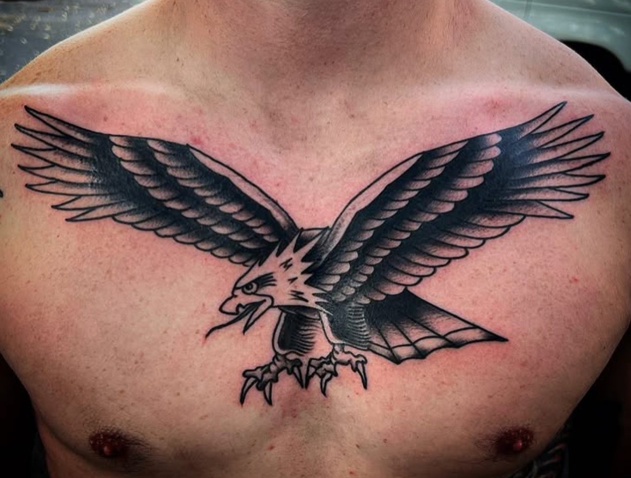 Tattoo of a fierce eagle with outstretched wings on a person's chest.
