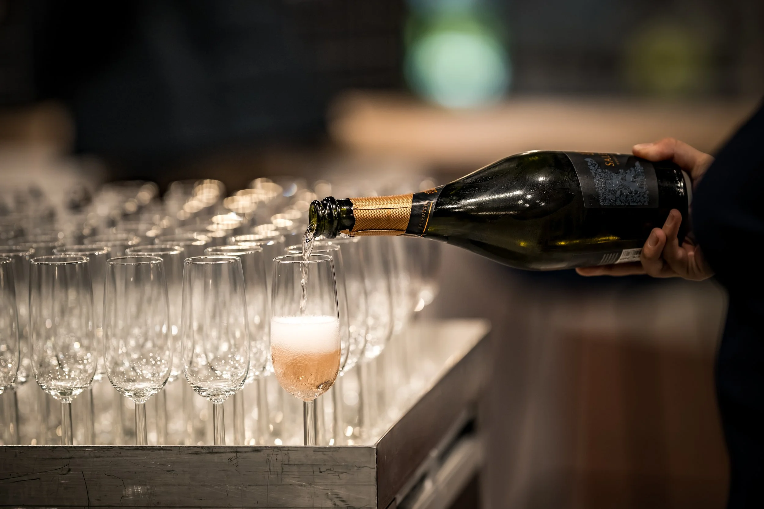 Persoon schenkt champagne in glazen op een bar of tafel.