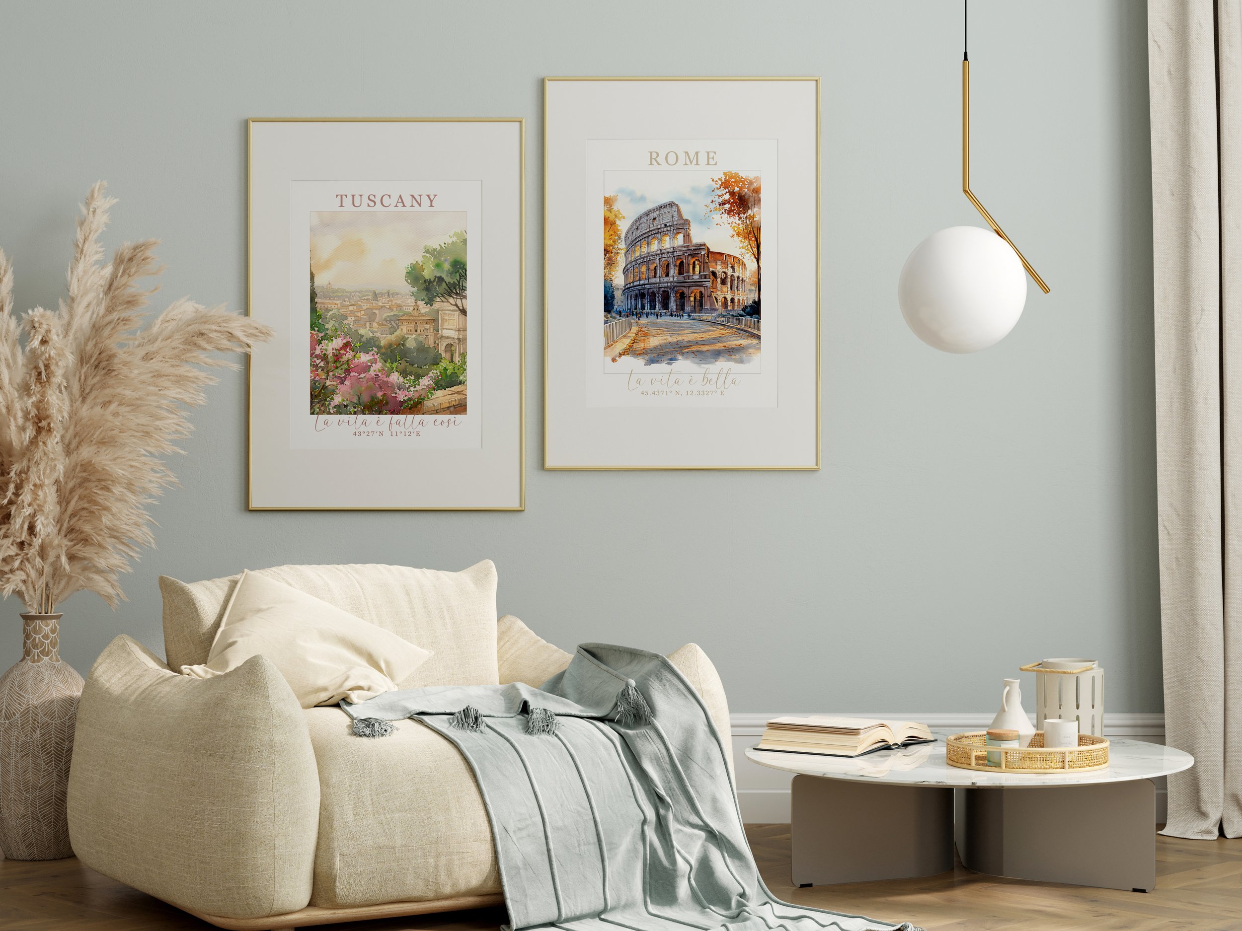 Modern living room with light green walls, two framed travel posters of Tuscany and Rome, a beige sofa with cushions and a throw blanket, a round coffee table with books and decorative items, large curtains, and a decorative vase with pampas grass.