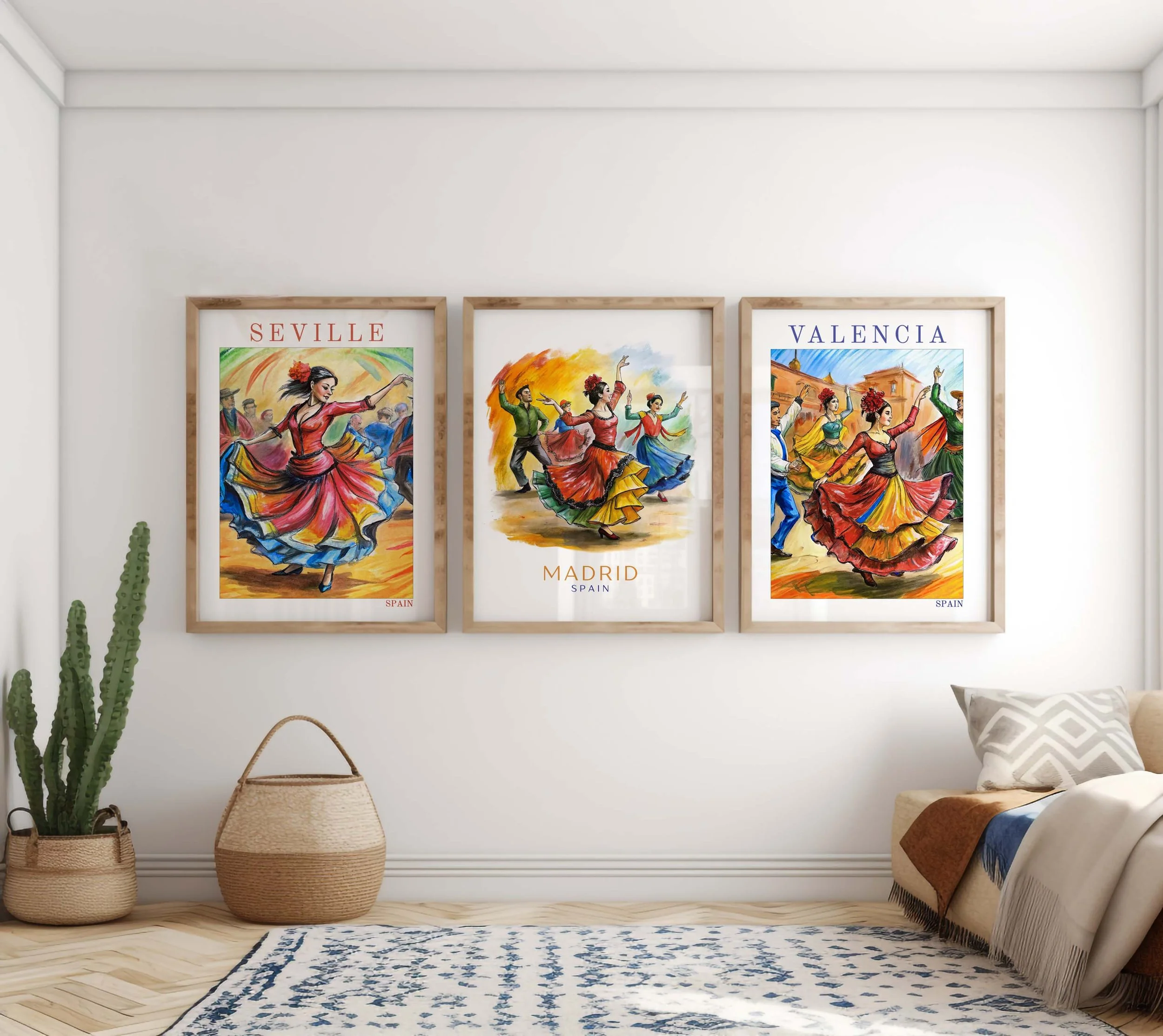 Three framed colorful posters of traditional Spanish dancers in vibrant costumes, titled 'Seville,' 'Madrid,' and 'Valencia,' hanging on a white wall in a living room with a cactus plant, woven basket, beige sofa with pillows, and a blue and white patterned rug.