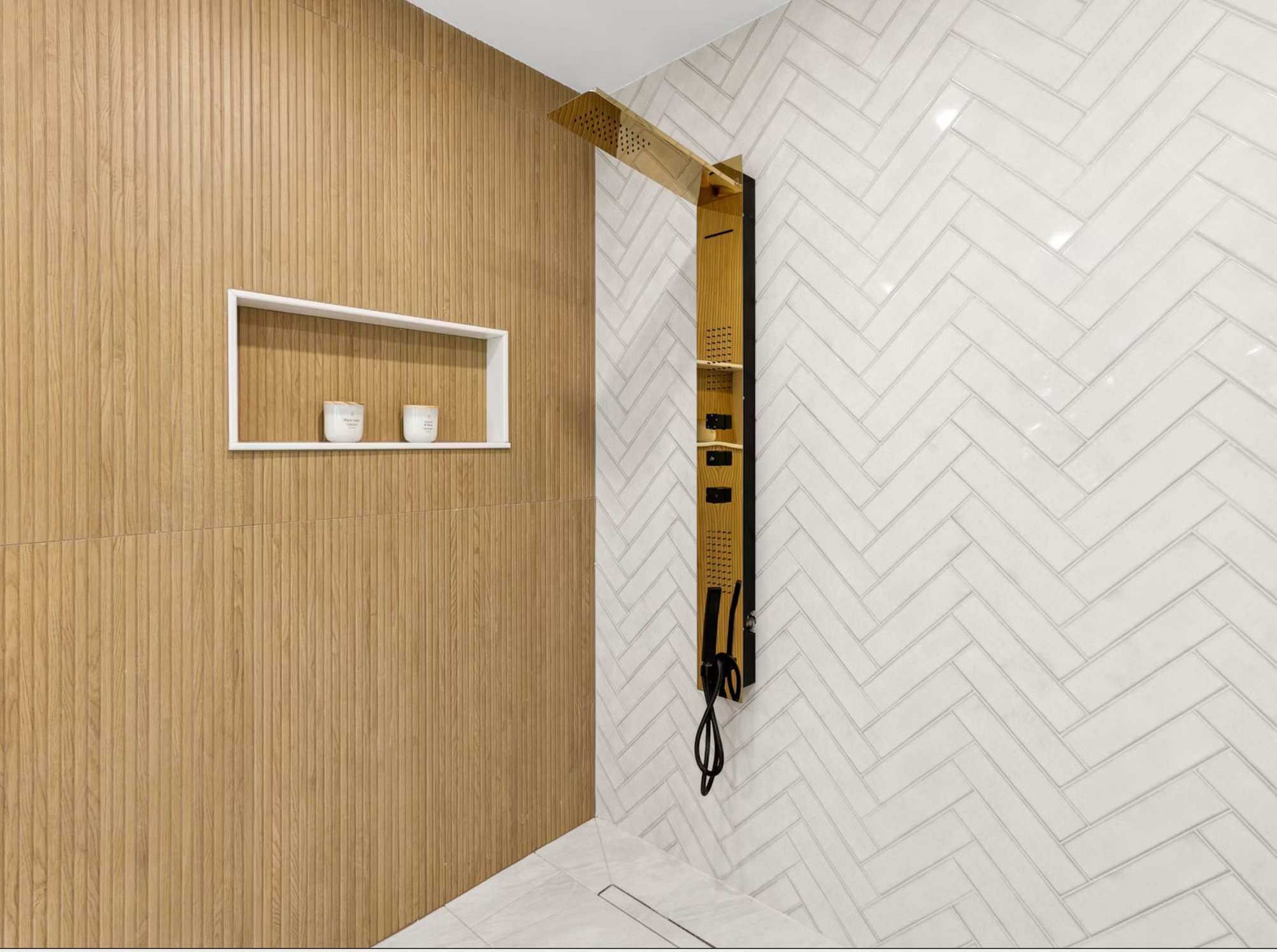 A modern interior corner with a wooden slatted wall on the left, white herringbone patterned wall on the right, a built-in rectangular shelf with two white containers, and a vertical wooden rack with black hooks holding a gym resistance band.