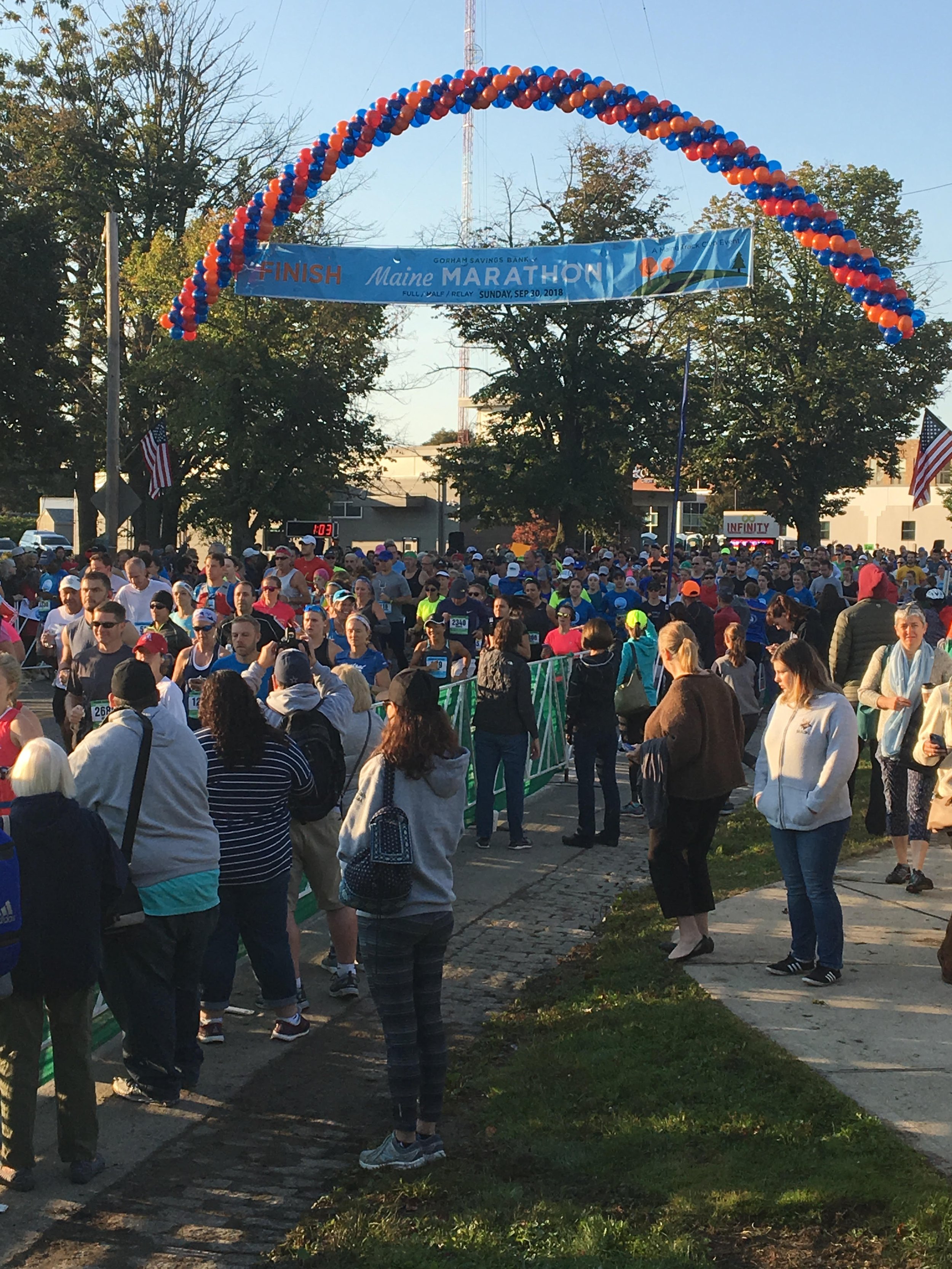 Crowd at the Maine Marathon 2018 finish line with blue and orange balloon arch.
