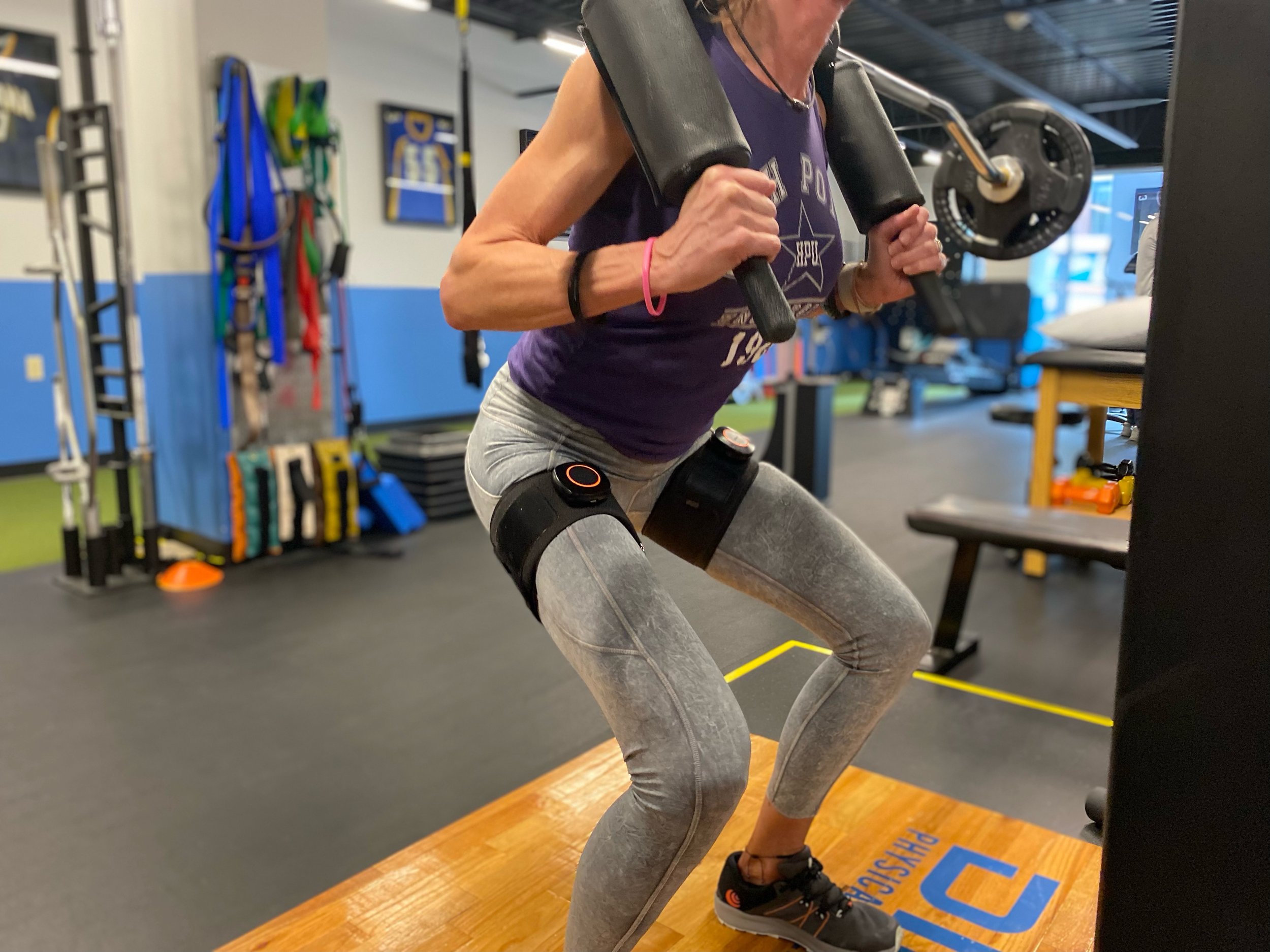 Person doing leg exercise on exercise machine in gym wearing athletic clothing