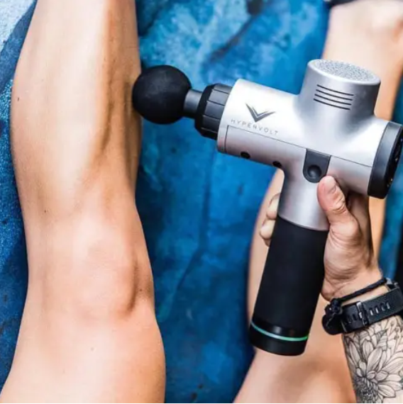 Person using a massage gun on an arm muscle