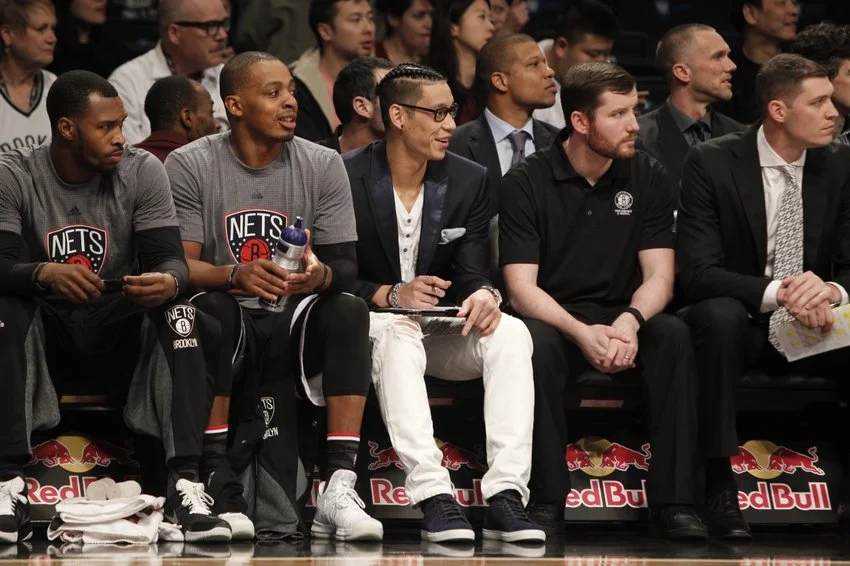 Brooklyn Nets players and staff on the bench during a basketball game.