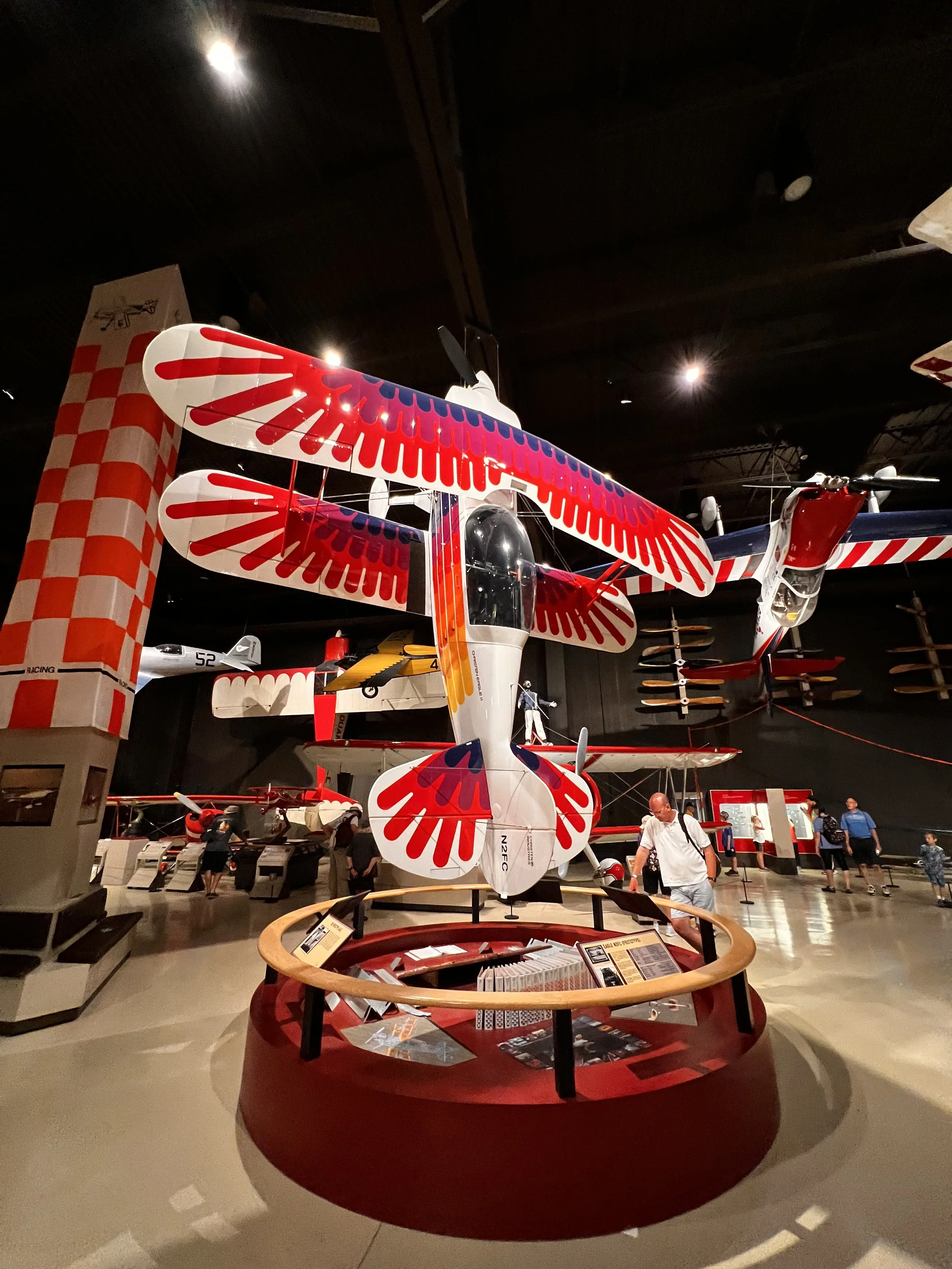 A display of a model aircraft with colorful red, blue, and white wings inside a museum.