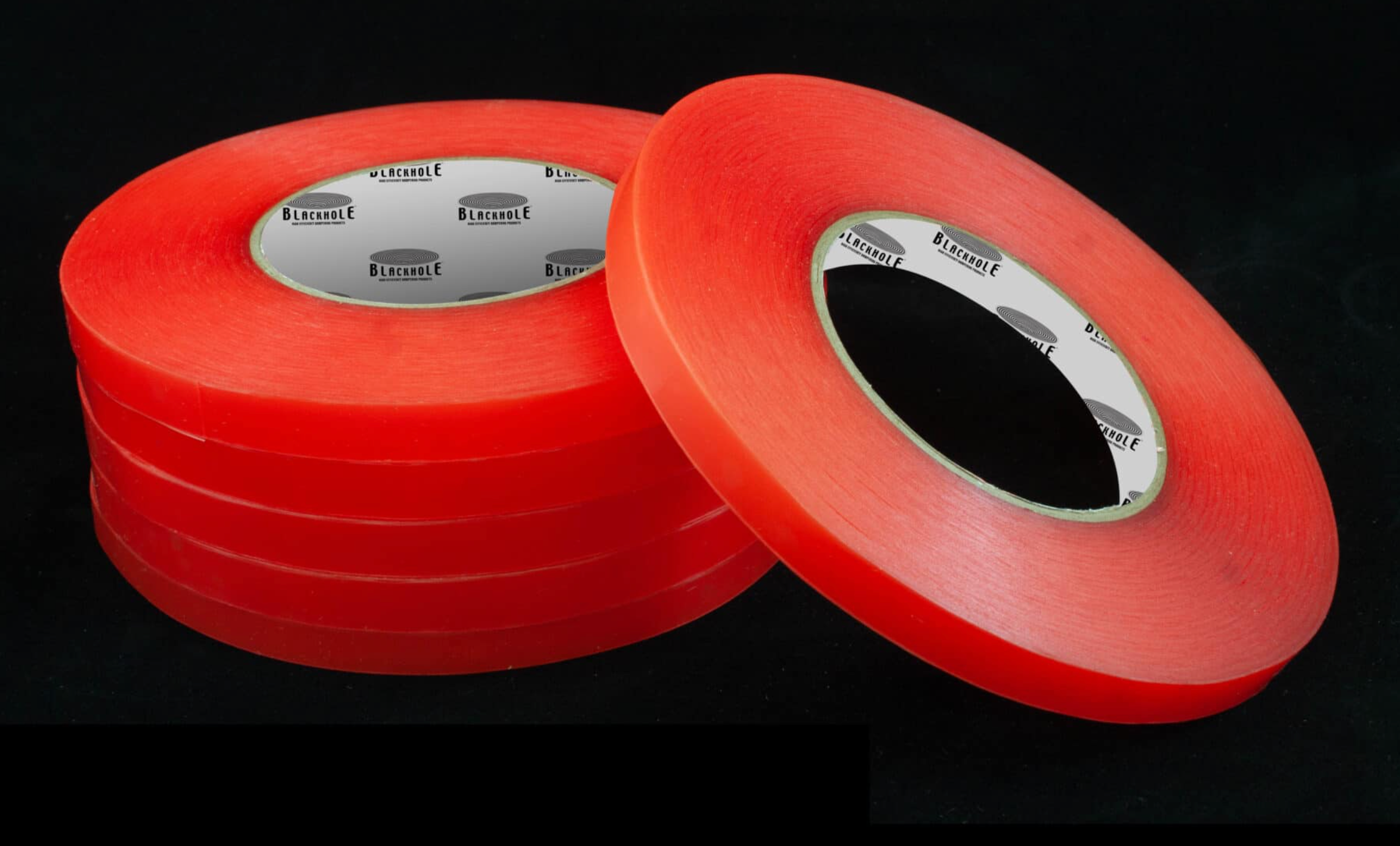 Stack of five red adhesive tapes and one loose tape on a black background.
