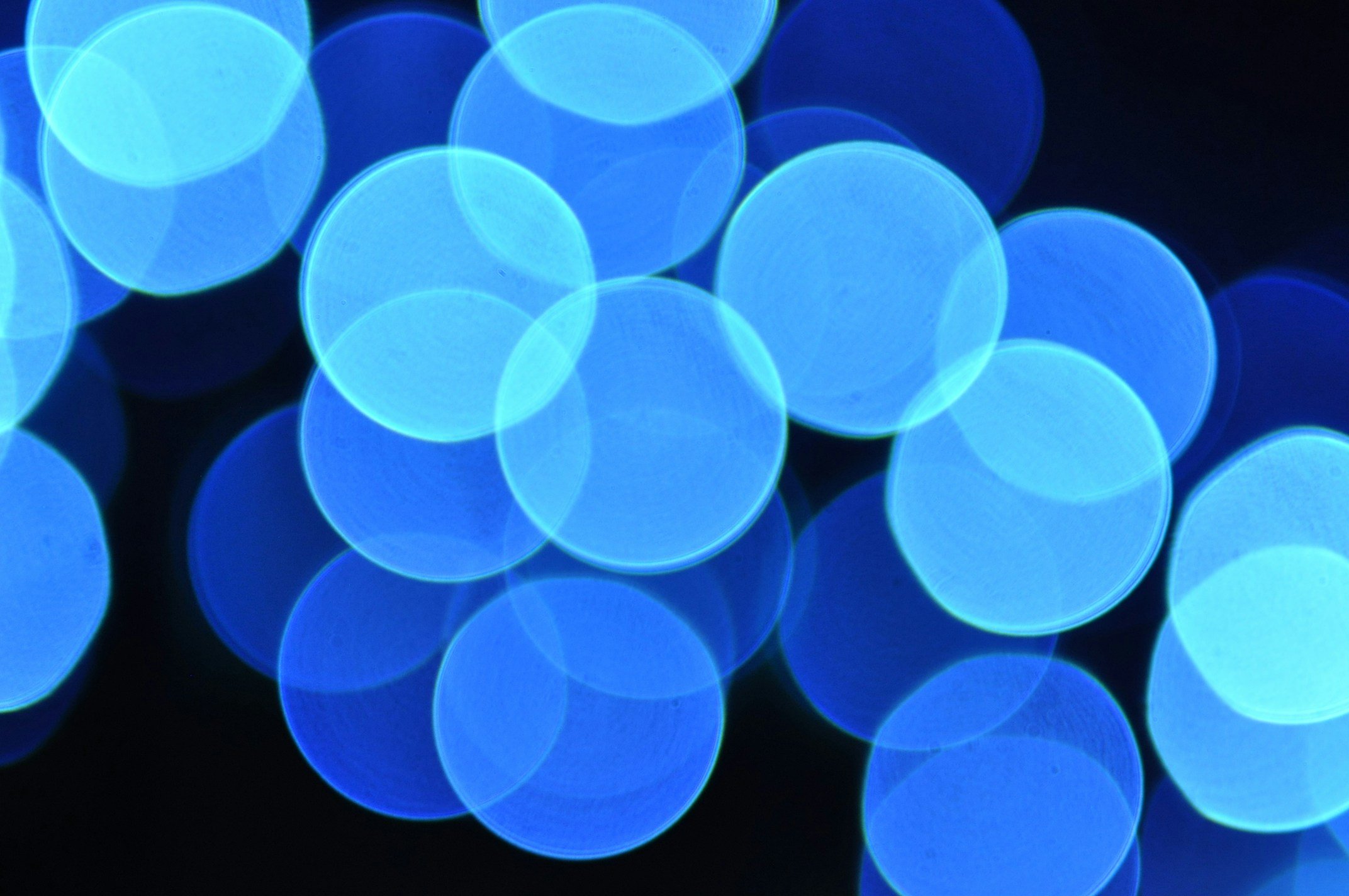 Blue bokeh lights in circular shapes on a dark background.