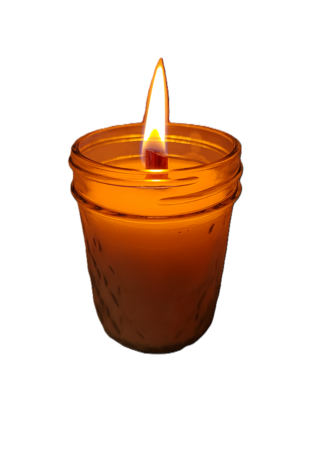 A lit candle in an orange glass container against a black background.