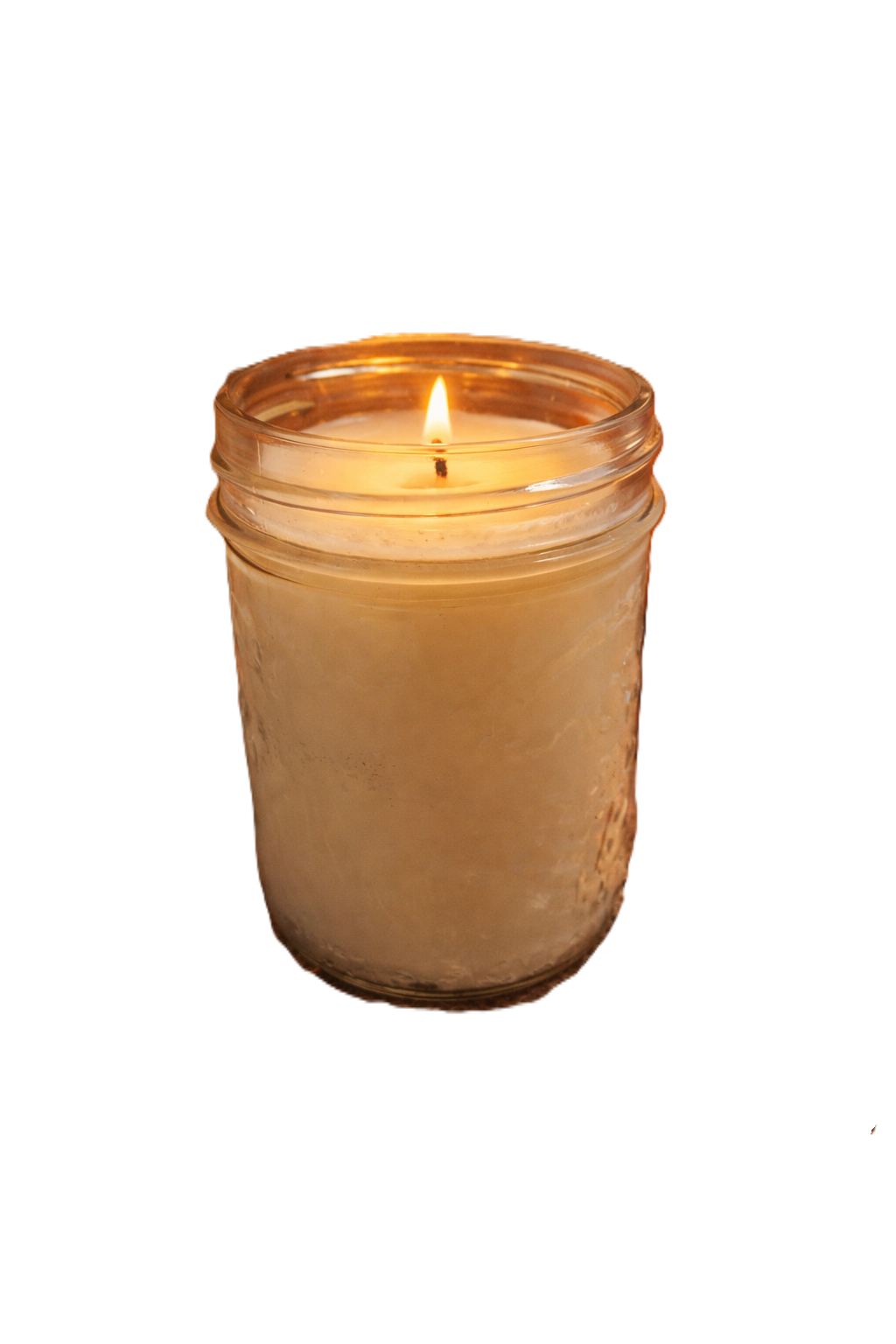 A lit white candle in a glass jar surrounded by autumn leaves, dried orange slices, star anise, cinnamon sticks, a pumpkin, pinecones, and warm bokeh lights in the background.