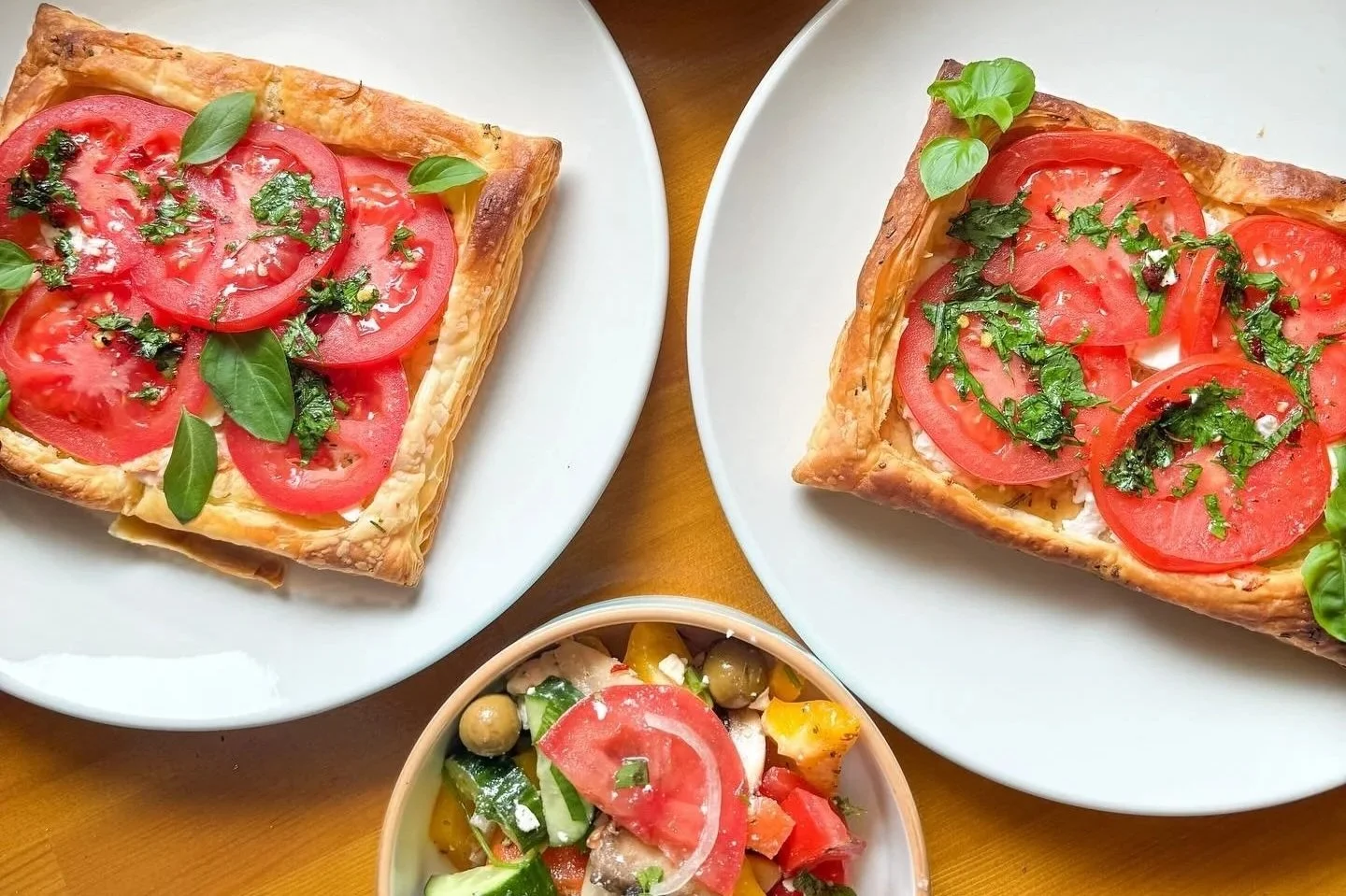 Flaky puff pastry topped with parsley walnut pesto, sliced summer tomatoes, feta and basil