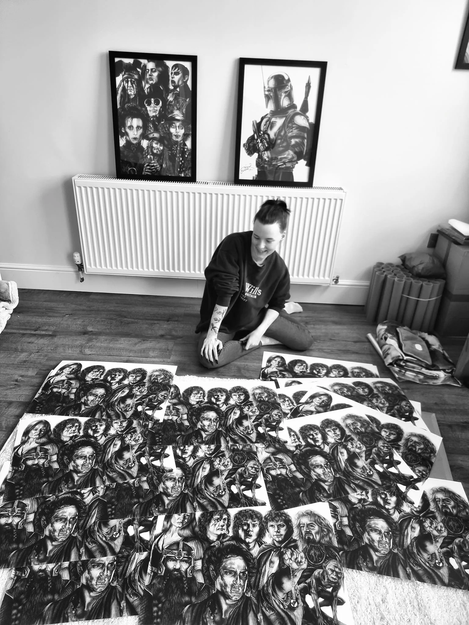 A woman sitting on the floor surrounded by numerous sketches or drawings of characters, with posters of popular characters on the wall behind her.