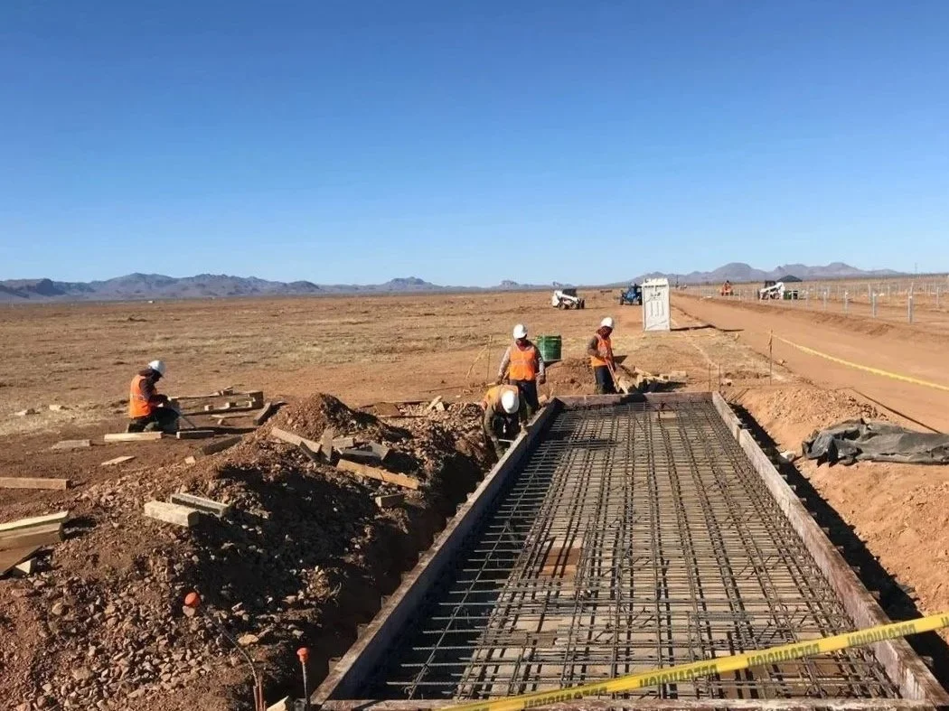 Aude Energia realizando trabajos de obra civil en el proyecto BNB Villahumada Solar I, con estructura de acero de refuerzo instalada para cimentación, en un sitio solar a cielo abierto. 