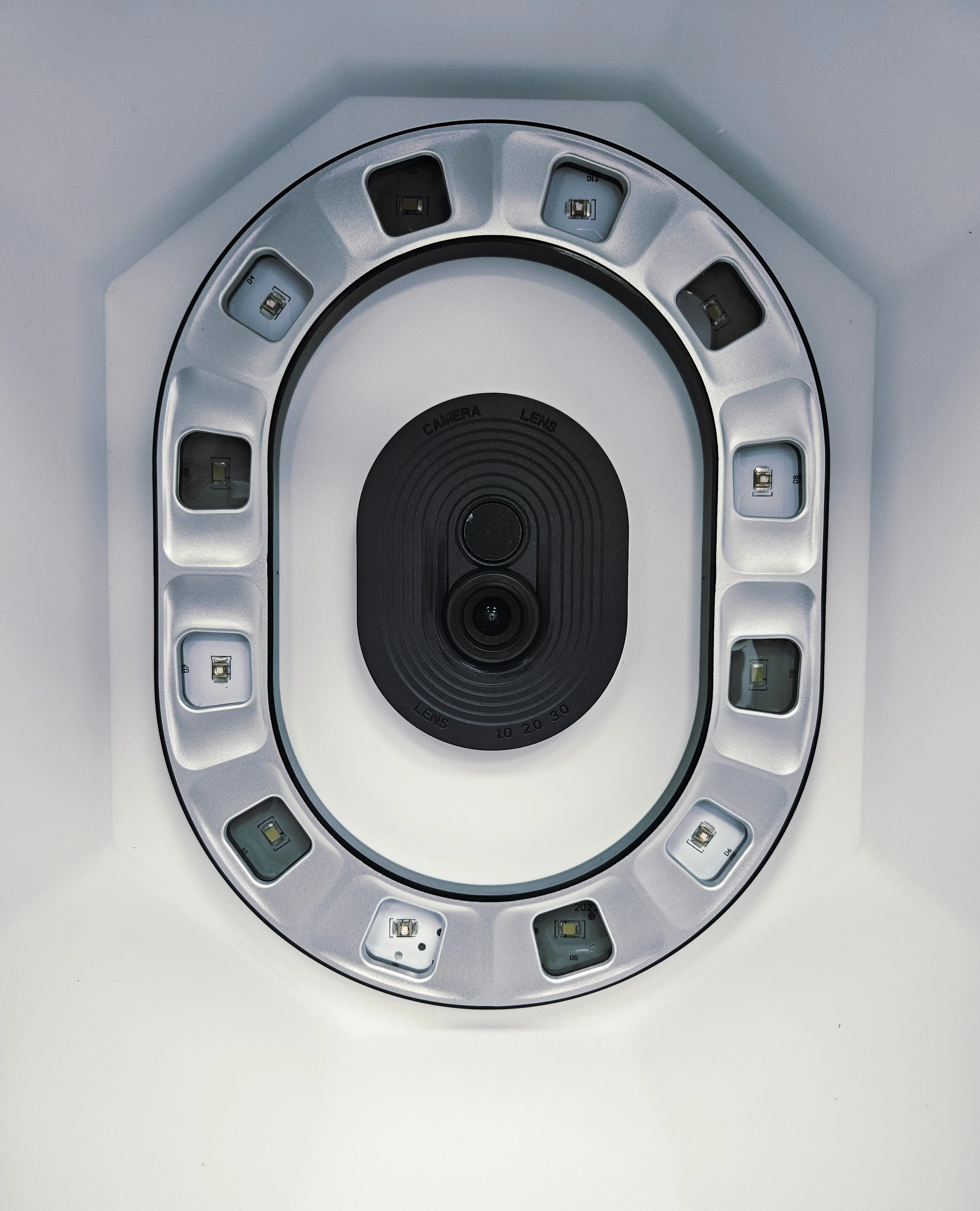 Ceiling-mounted digital camera with an oval ring of LED lights surrounding the lens.