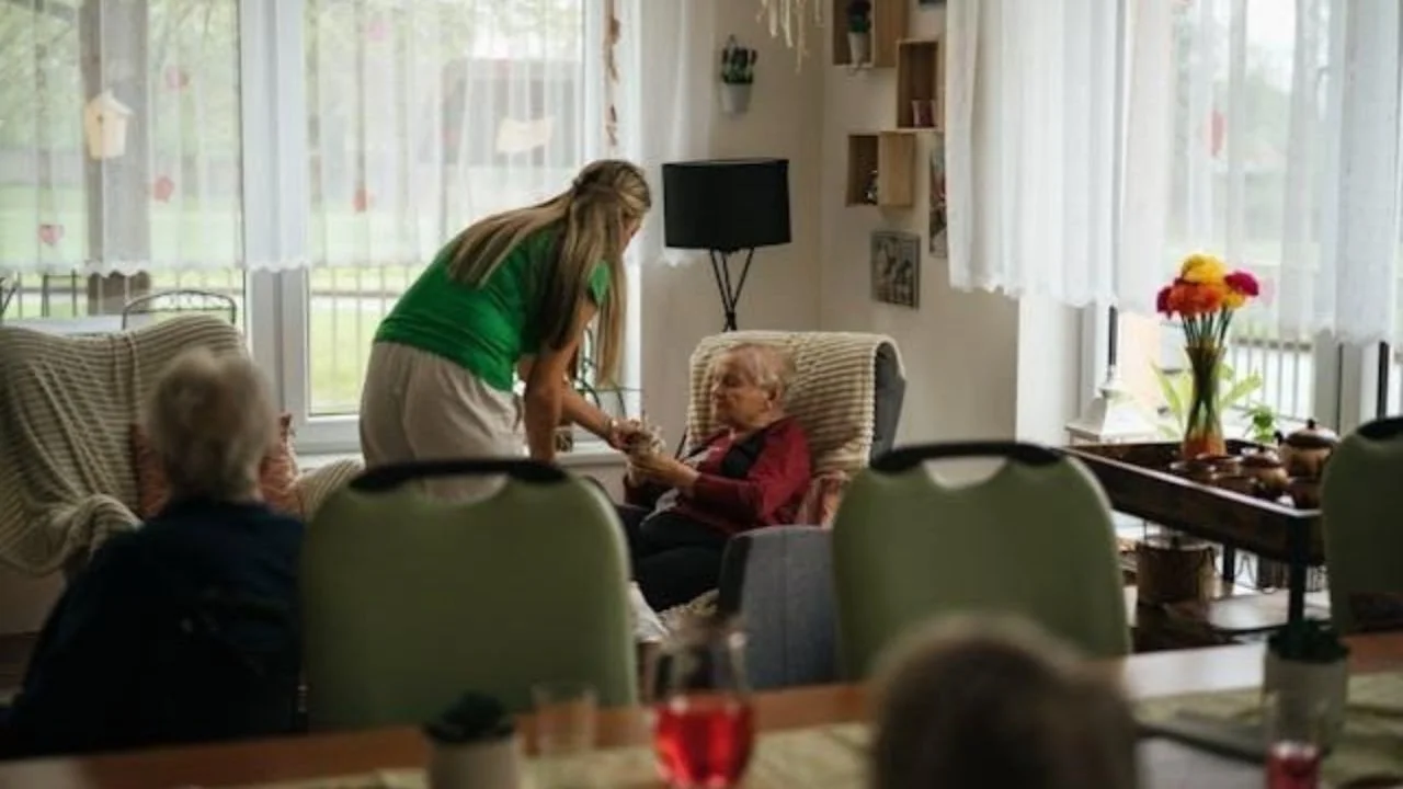 Caregiver assisting elderly resident in a warm assisted living home.
