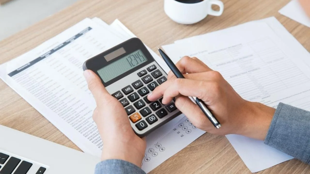 Person calculating expenses for taxation with documents and laptop.