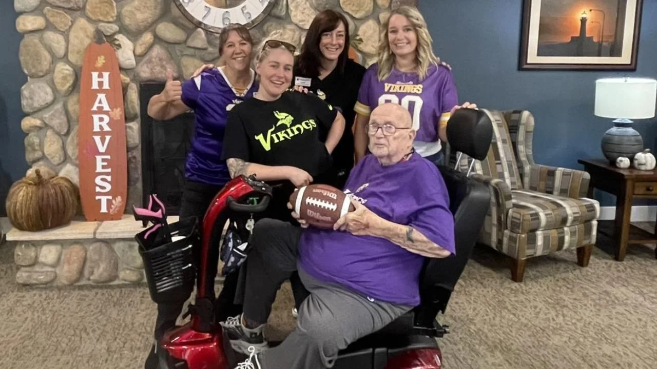 Assisted living staff posing indoors with seniors in a setting.
