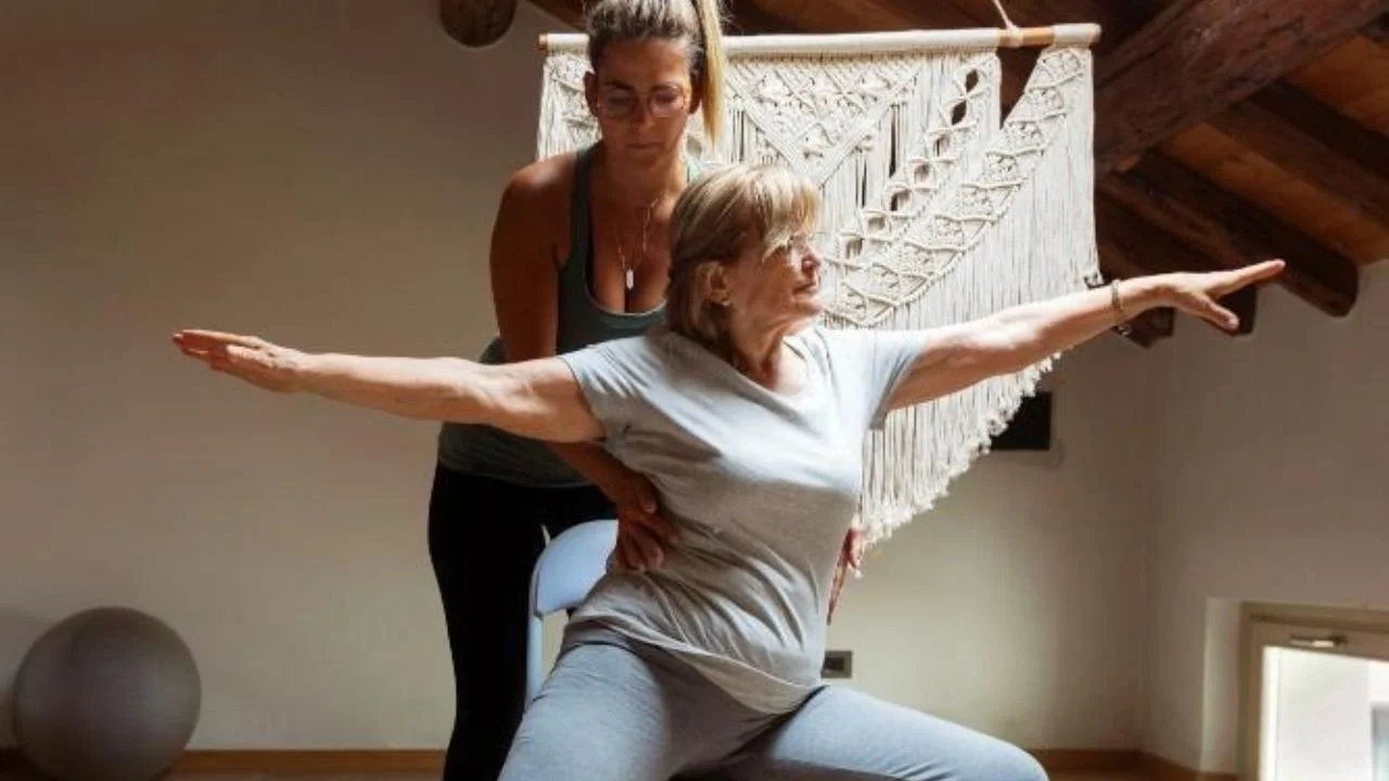 Senior practicing chair yoga with instructor’s support.