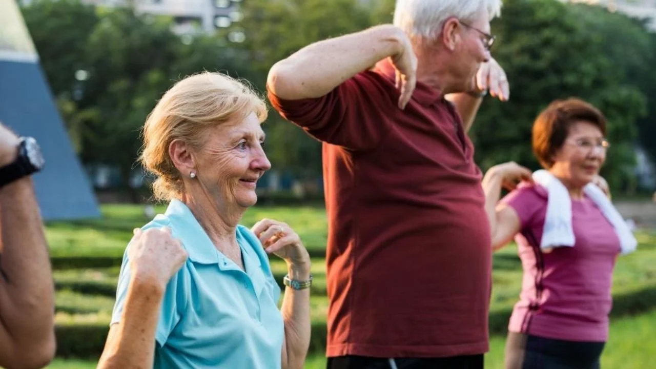 Older adults exercising together outdoors in city park.