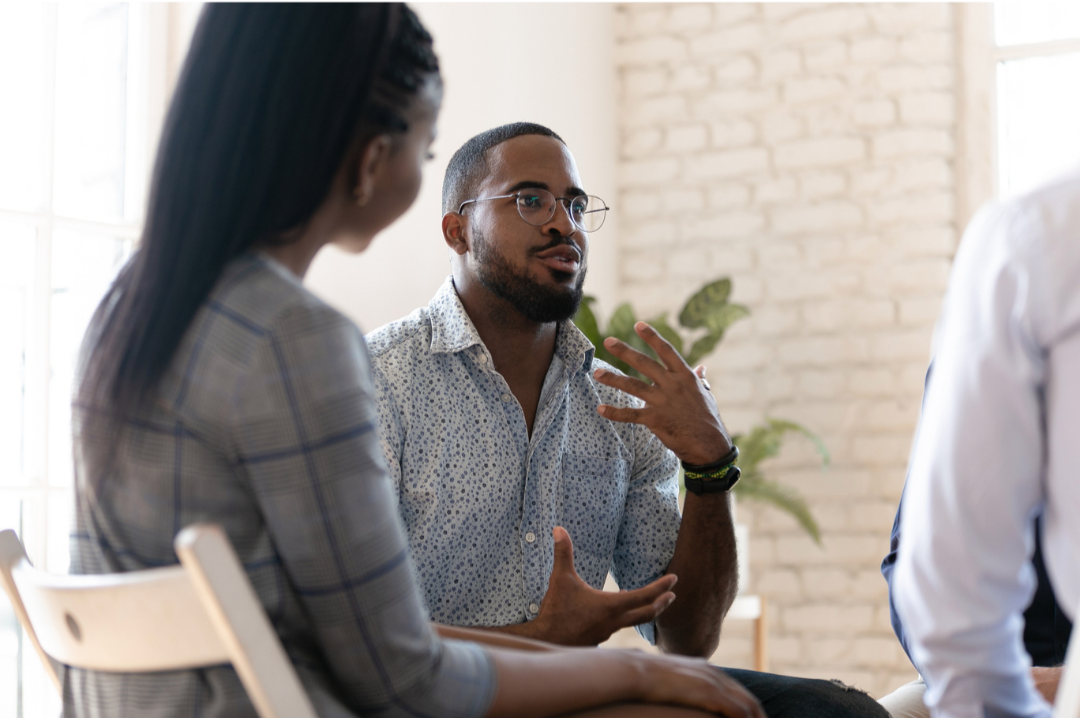 Black man in a group setting expressing himself