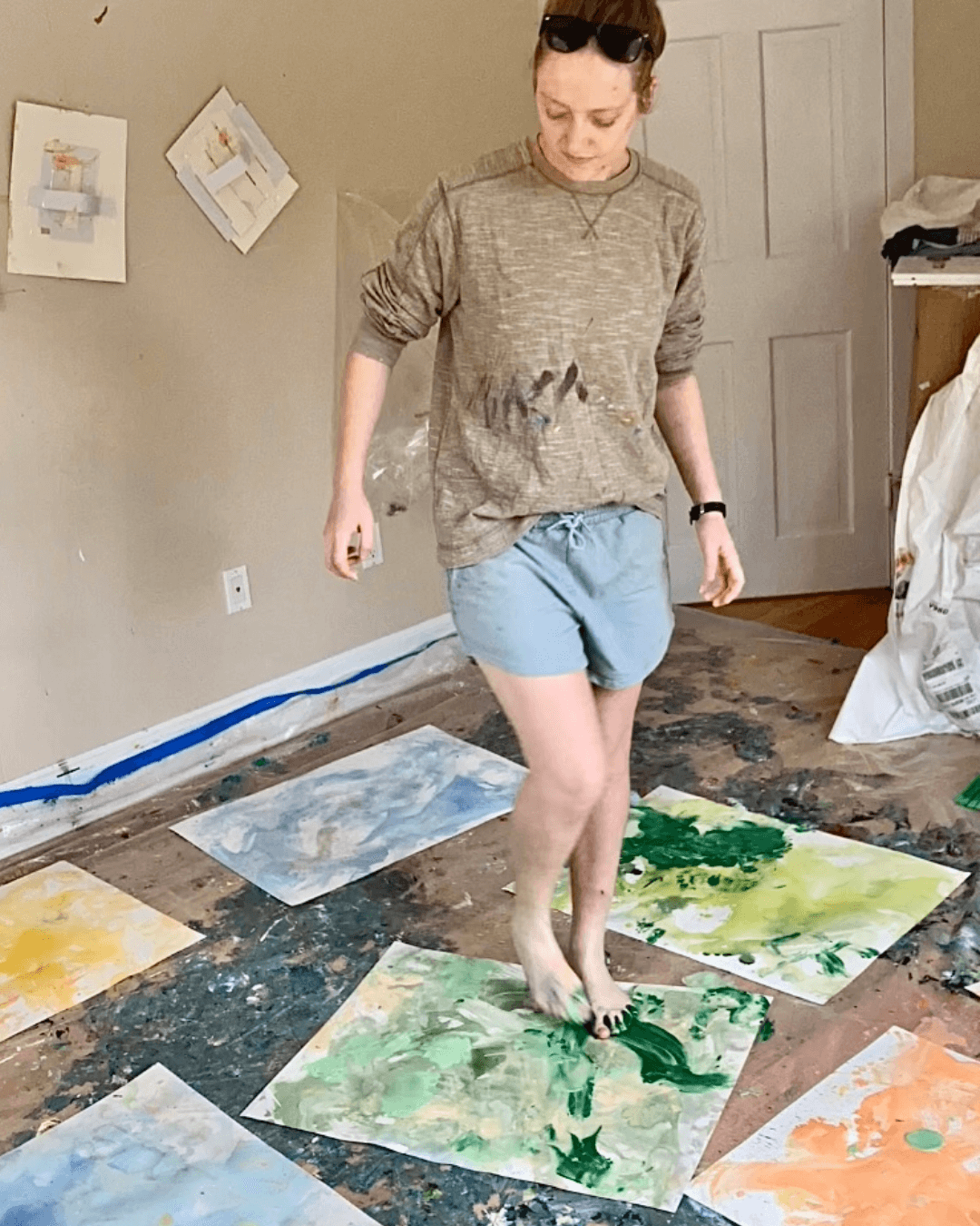 Image shows artist painting a series of artworks with her feet.