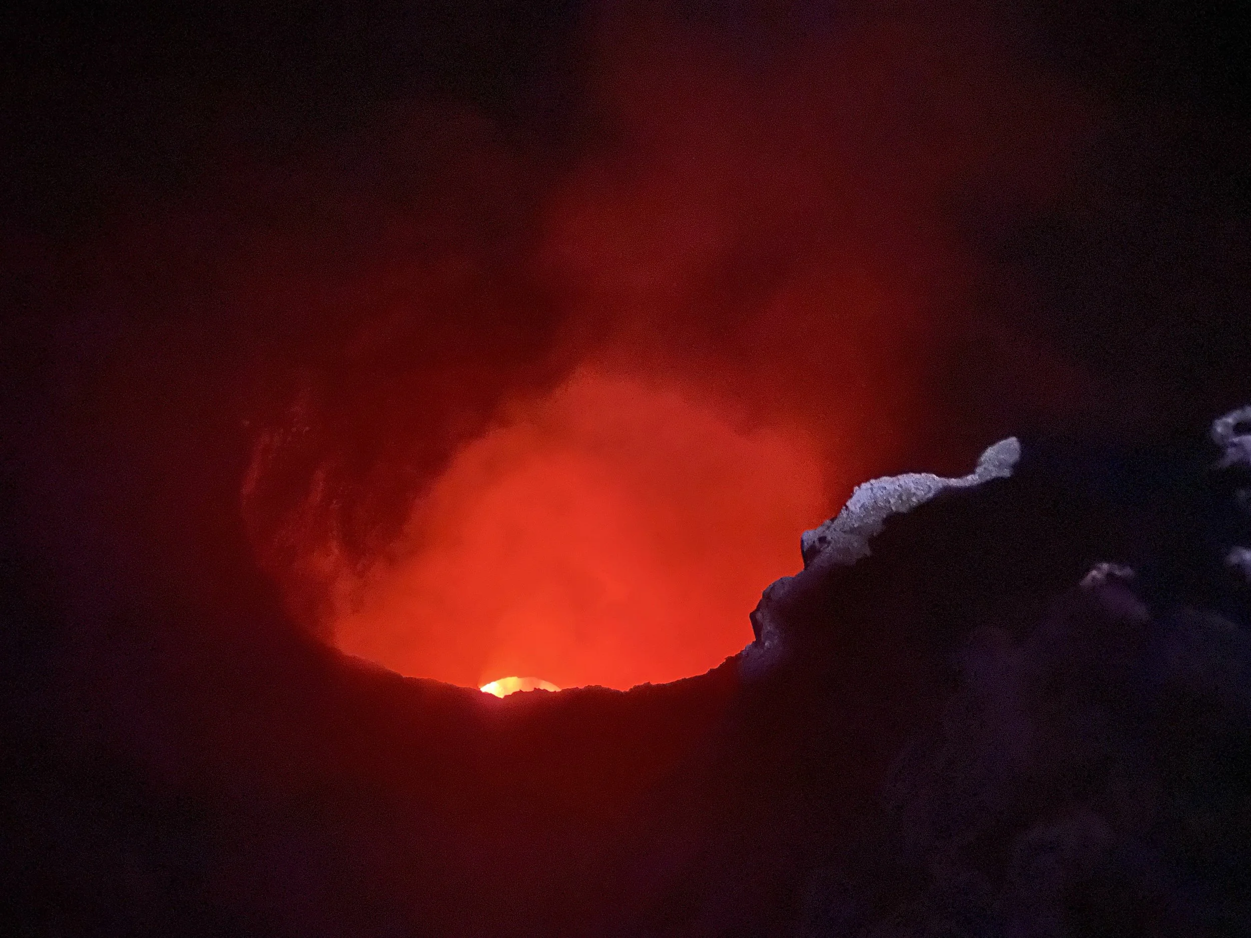 Glowing red lava visible inside Masaya Volcano crater at night in Nicaragua, with dark rock edges surrounding the illuminated crater.