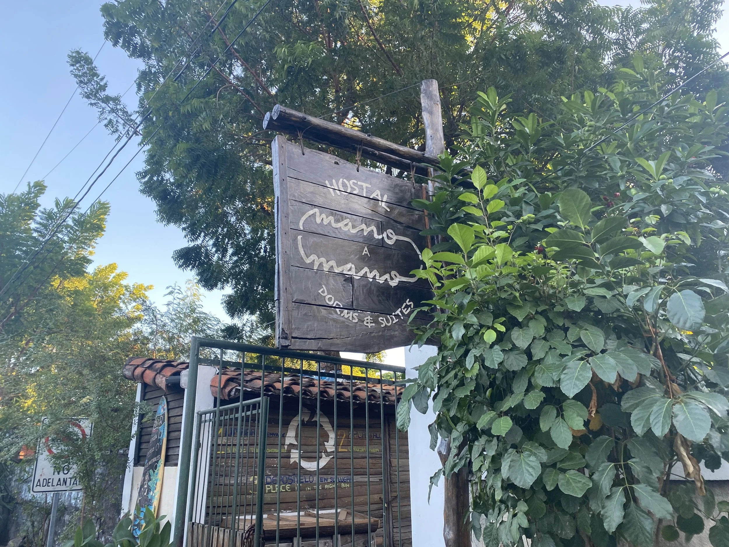 Wooden hostel sign outside a small guesthouse in Nicaragua surrounded by greenery and trees