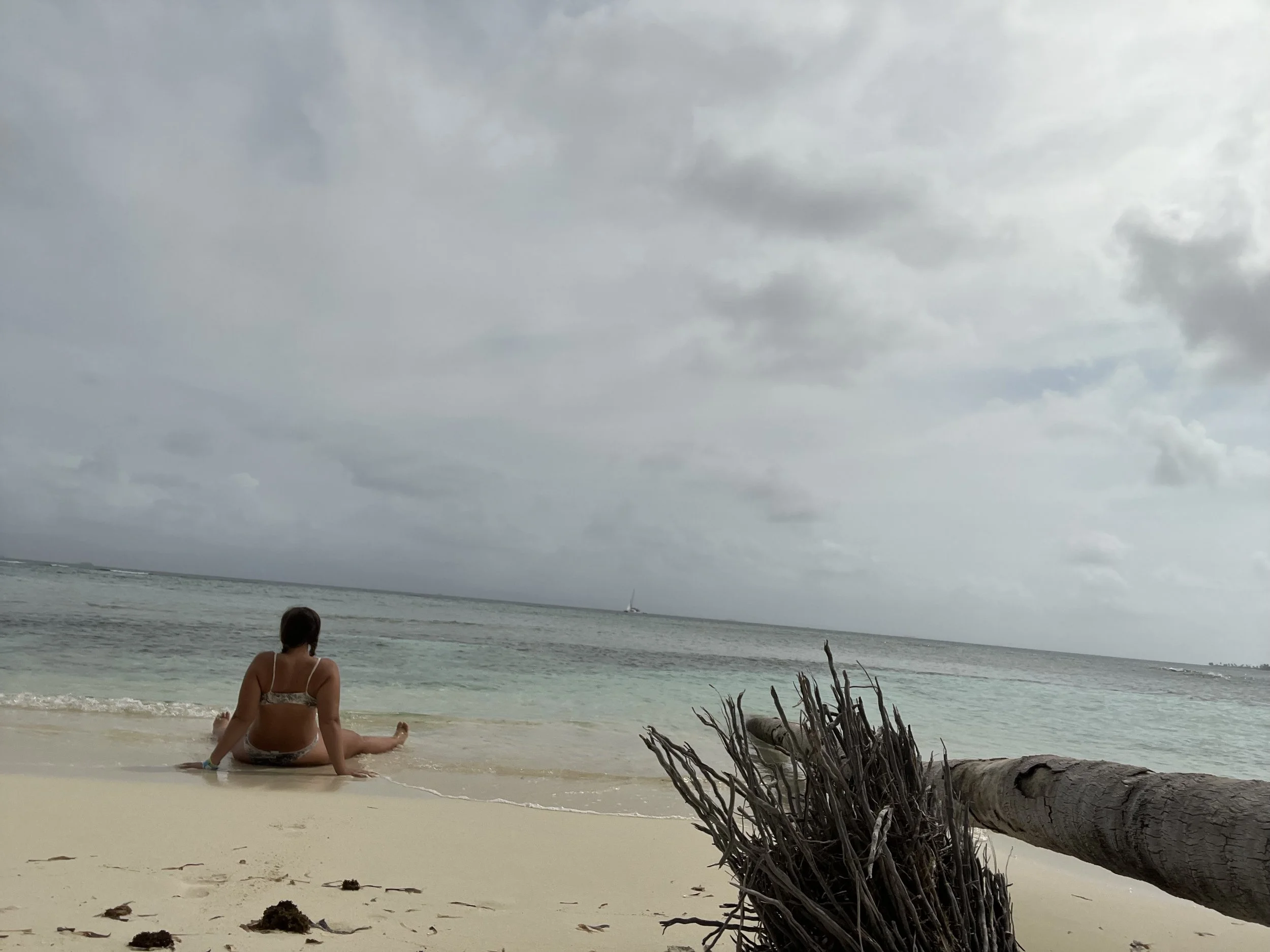 Woman sitting alone on beach in San Blas Islands Panama looking out at ocean during quiet travel moment