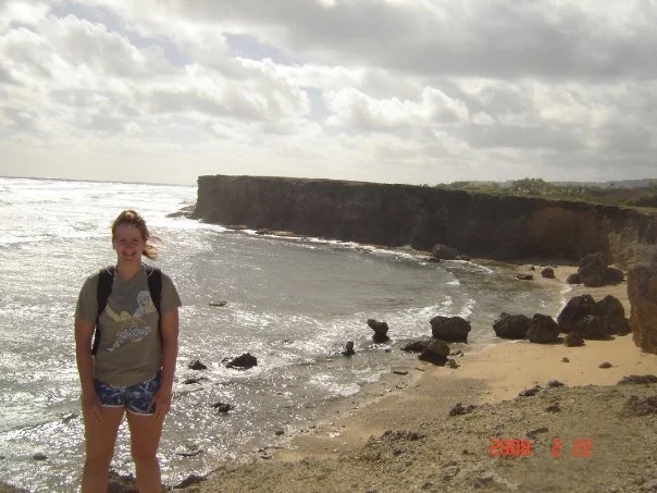 Young solo traveler standing on a beach in Barbados in 2008, overlooking the ocean and rocky coastline during her first independent trip abroad.