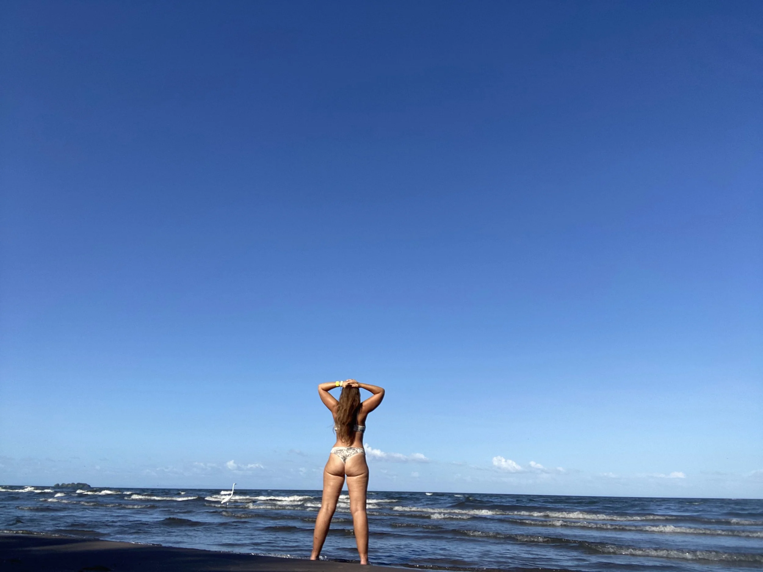 Woman standing on a beach in Ometepe, Nicaragua looking out over Lake Nicaragua on a clear day