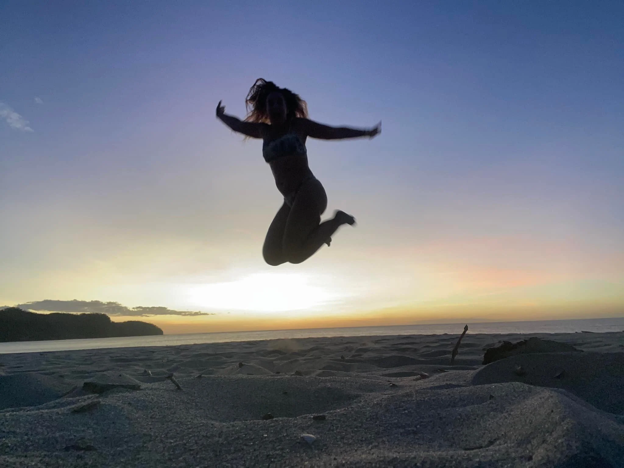 Silhouette of a traveler jumping at sunset on a beach in Costa Rica.