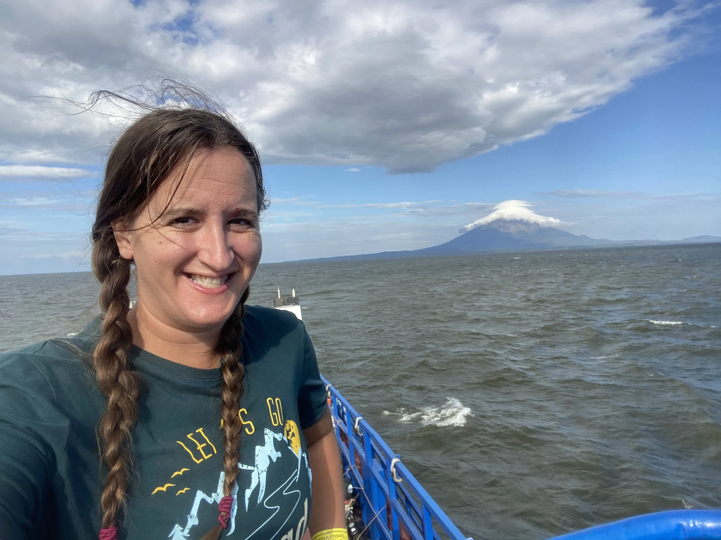 Solo female traveler on a ferry in Nicaragua with a volcano in the background on Ometepe Island