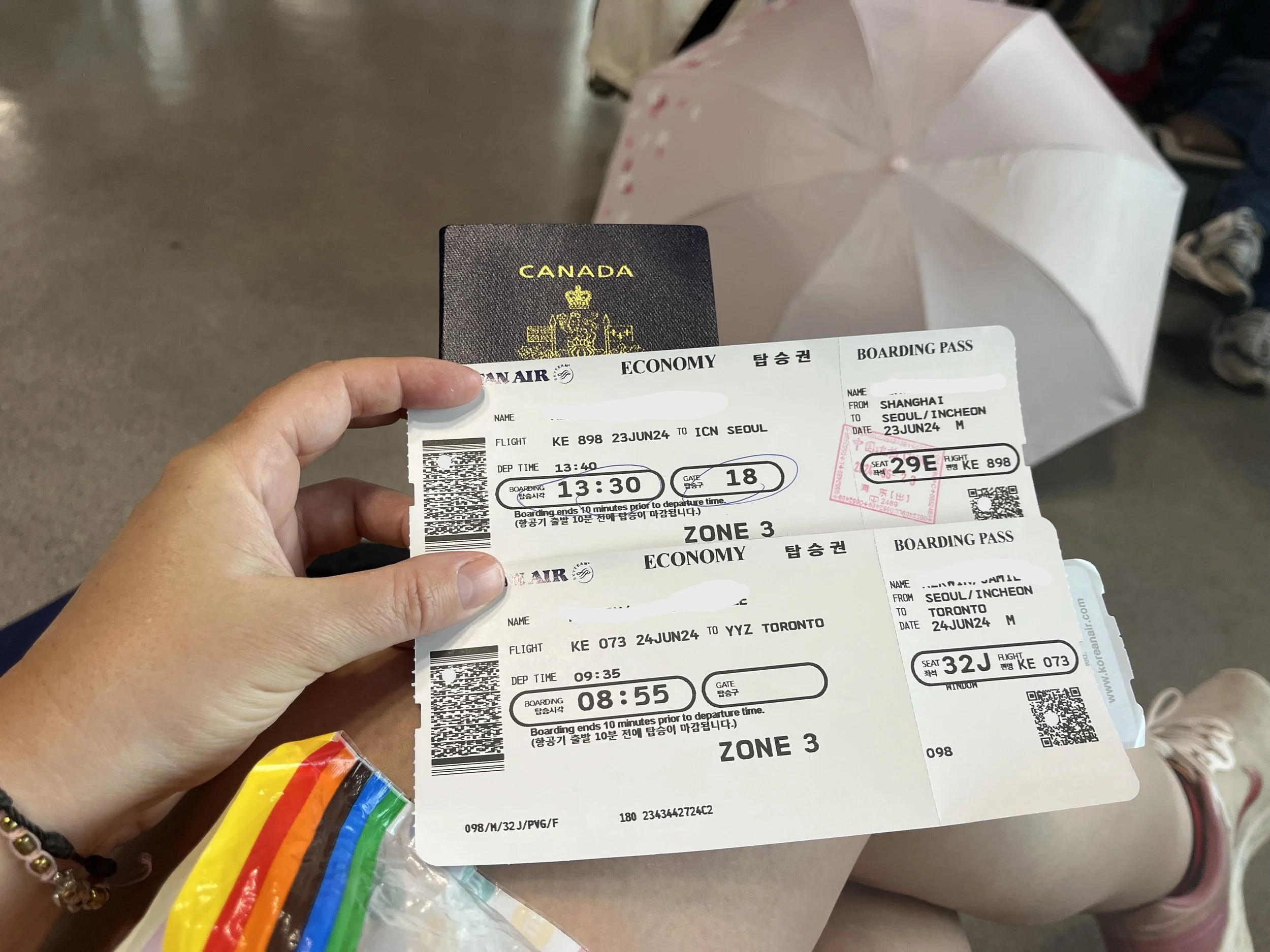 A Canadian passport and two boarding passes being held in an airport before an international flight.