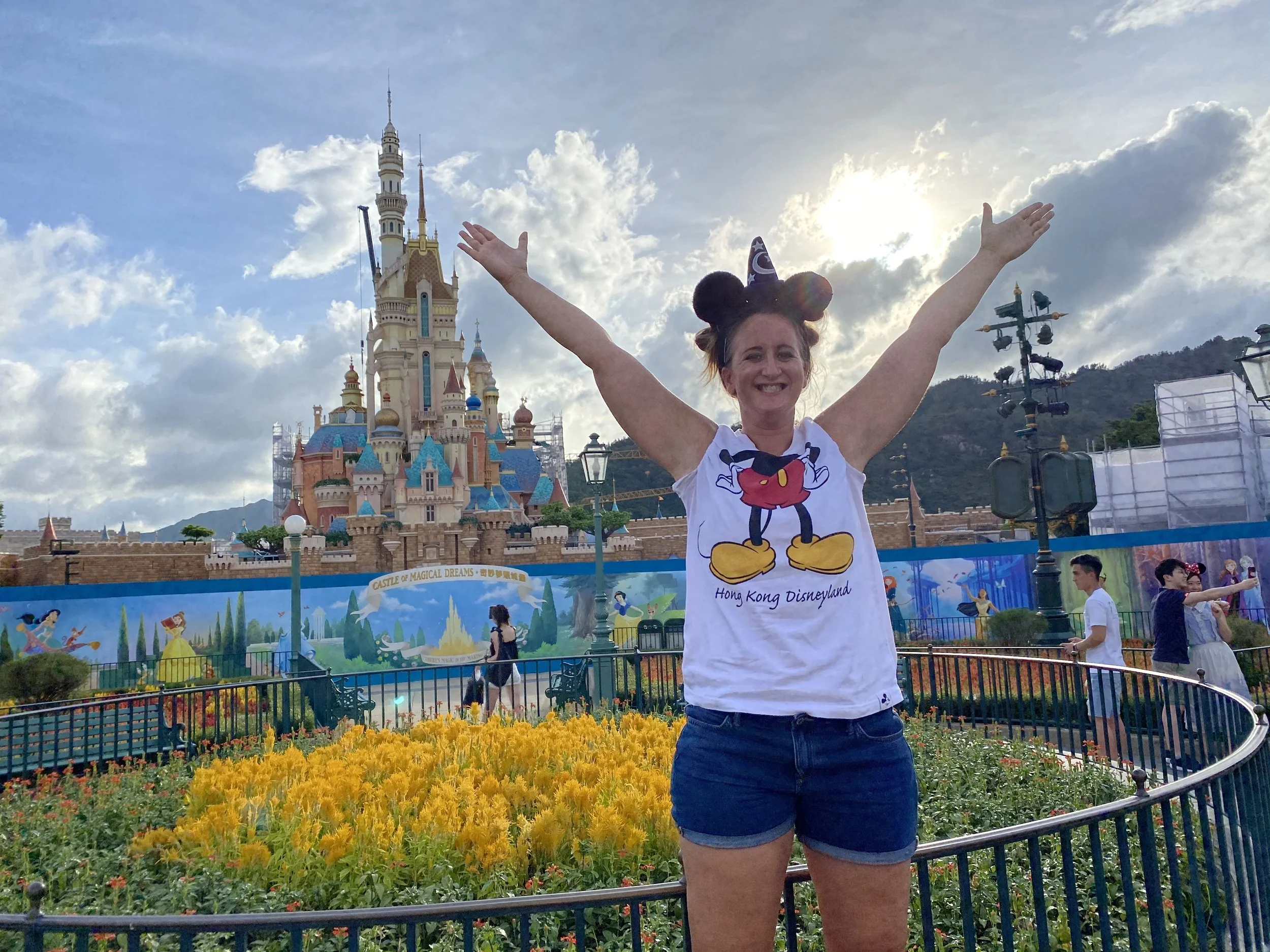 Woman smiling at Hong Kong Disneyland castle during COVID with reduced crowds