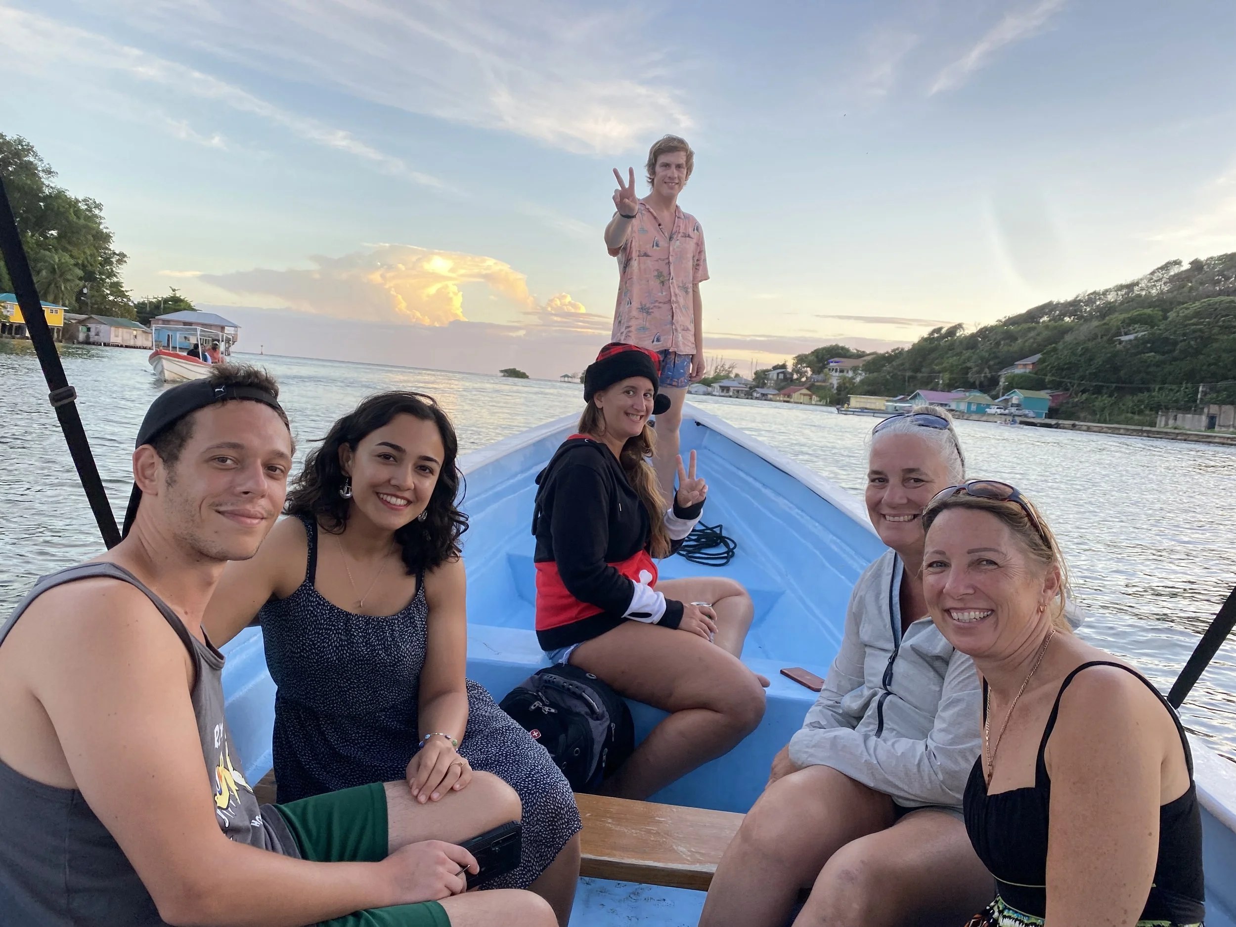 Group of travelers sitting together on a small boat in Roatán, Honduras at sunset before a Christmas boat parade