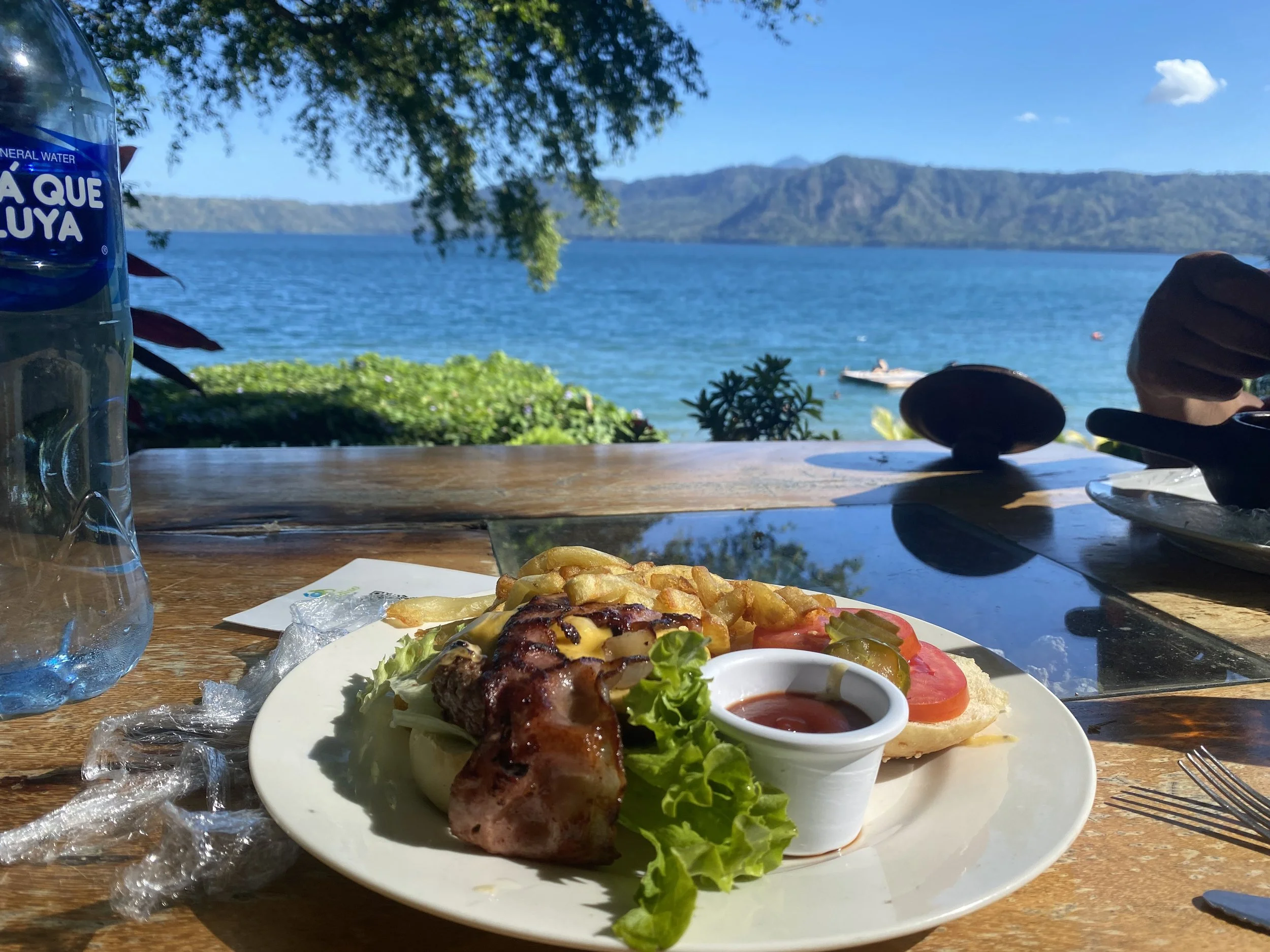 Meal with burger and fries on a table overlooking a lake and mountains in Nicaragua with scenic water view