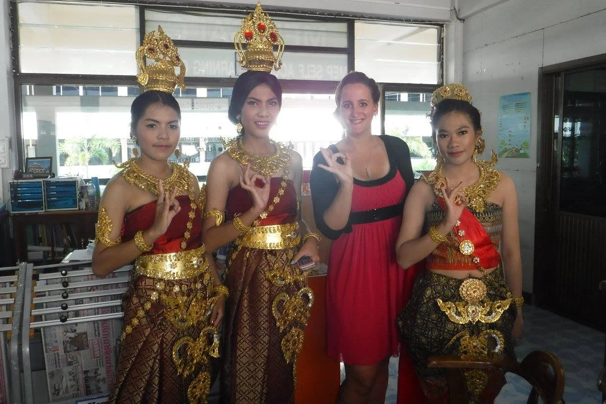 A foreign woman teacher posing with students dressed in traditional Thai clothing during a school event in Thailand.