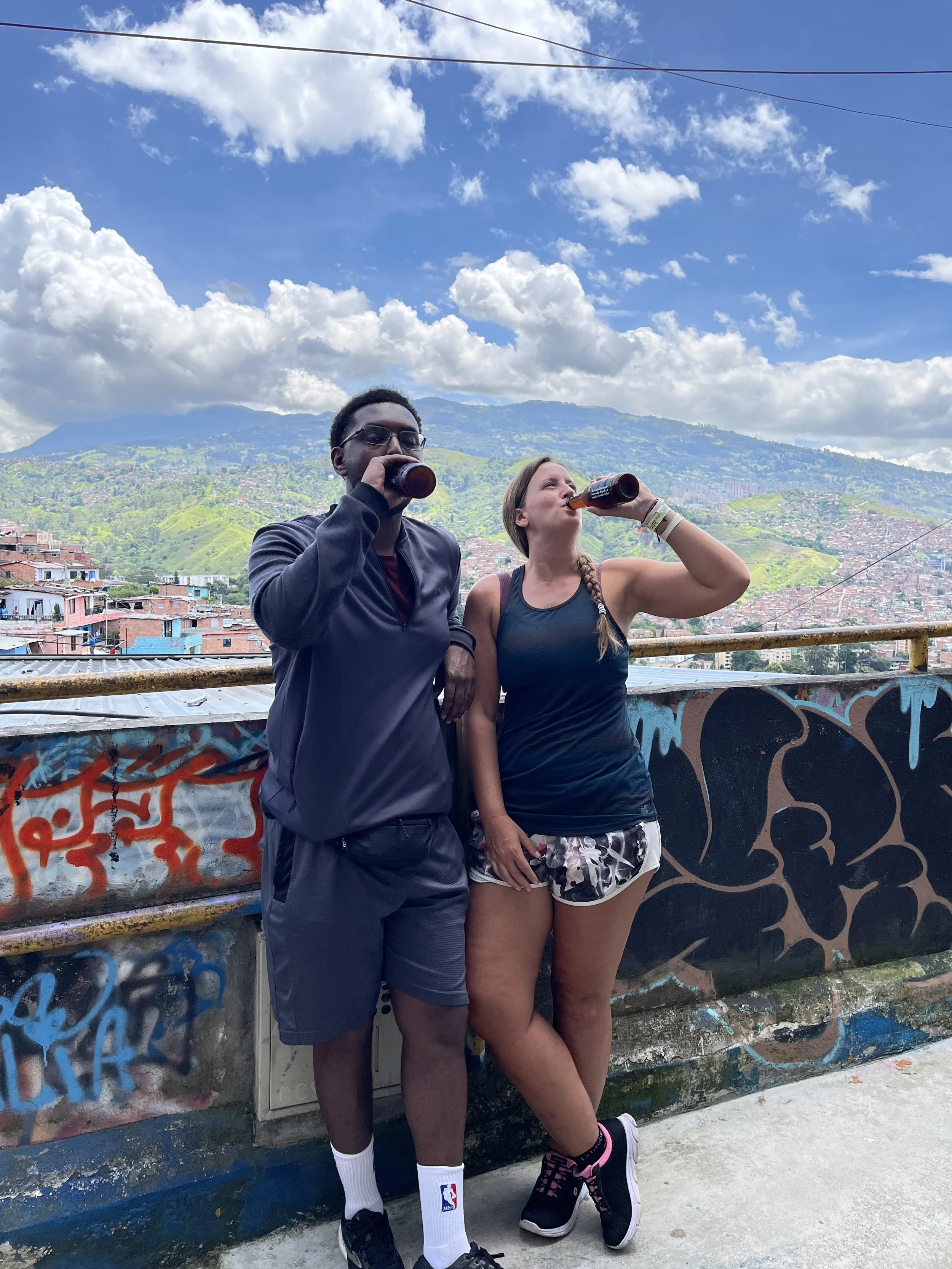 Sharing a local beer with a fellow traveller at a scenic viewpoint in Medellín, Colombia, after meeting on a guided tour and becoming friends.